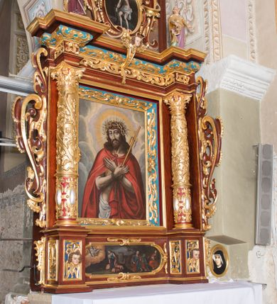 Zdjęcie nr 1: Ołtarz architektoniczny, jednoosiowy, jednokondygnacyjny ze zwieńczeniem. Ołtarz murowany, prostopadłościenny z kamienną mensą. Antepedium drewniane, w polu którego ozdobny, płaskorzeźbiony monogram Chrystusa na niebieskim tle wraz z dekoracją ornamentalną w narożach pola. Pole ujęte ozdobną ramą z płaskorzeźbionym ornamentem z wici roślinnej na jasnoniebieskim tle. Drewniane retabulum ustawione na cokole. W polu obraz z przedstawieniem Modlitwy w Ogrójcu w kształcie leżącego prostokąta o krótszych bokach zakończonych łukiem nadwieszonym. Nastawa flankowana parą kolumn podtrzymujących wyłamane nad osią główną belkowanie. W polu głównym obraz Ecce Homo, a na zasuwie obraz św. Antoniego Padewskiego. Zwieńczenie w formie owalu ujętego ażurową dekoracją formowaną z ornamentu małżowinowo-chrząstkowego na tle kwadratowej ramy. W polu obraz Chrystusa u słupa, po bokach figury, po lewej św. Mikołaja, po prawej św. Doroty, na szczycie figura św. Józefa. Partie cokołów ozdobione płycinami z uskrzydlonymi główkami aniołów w polu, po bokach dekorowane ornamentem małżowinowo-chrząstkowym. Zasadnicza część nastawy ujęta po bokach uszami z ornamentem o formach małżowinowo-chrząstkowych, z czego prawy złożony, dostosowany do południowego filaru kościoła. Trzony kolumn w dolnej partii ozdobione kartuszami o fantazyjnych wycięciach z motywami kaboszonów, w górnej partii pokryte dekoracją w formie wici winnej latorośli. W partii fryzu oraz pod gzymsem ornamentyka roślinna. Pośrodku belkowania motyw dekoracyjnego spływu z uskrzydloną główką aniołka z podwiązaną chustą pod szyją. Pole środkowe w formie prostokątnej wnęki ujętej profilowanymi ramami z czego wewnętrzna ozdobiona ornamentem małżowinowo-chrząstkowym. Polichromia struktury ołtarza utrzymana w odcieniach ciemnego brązu i czerwieni, partie w tle ornamentów niebieskie. Ornamentyka i elementy detalu architektonicznego złocone i srebrzone. 

