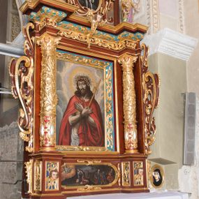 Zdjęcie nr 1: Ołtarz architektoniczny, jednoosiowy, jednokondygnacyjny ze zwieńczeniem. Ołtarz murowany, prostopadłościenny z kamienną mensą. Antepedium drewniane, w polu którego ozdobny, płaskorzeźbiony monogram Chrystusa na niebieskim tle wraz z dekoracją ornamentalną w narożach pola. Pole ujęte ozdobną ramą z płaskorzeźbionym ornamentem z wici roślinnej na jasnoniebieskim tle. Drewniane retabulum ustawione na cokole. W polu obraz z przedstawieniem Modlitwy w Ogrójcu w kształcie leżącego prostokąta o krótszych bokach zakończonych łukiem nadwieszonym. Nastawa flankowana parą kolumn podtrzymujących wyłamane nad osią główną belkowanie. W polu głównym obraz Ecce Homo, a na zasuwie obraz św. Antoniego Padewskiego. Zwieńczenie w formie owalu ujętego ażurową dekoracją formowaną z ornamentu małżowinowo-chrząstkowego na tle kwadratowej ramy. W polu obraz Chrystusa u słupa, po bokach figury, po lewej św. Mikołaja, po prawej św. Doroty, na szczycie figura św. Józefa. Partie cokołów ozdobione płycinami z uskrzydlonymi główkami aniołów w polu, po bokach dekorowane ornamentem małżowinowo-chrząstkowym. Zasadnicza część nastawy ujęta po bokach uszami z ornamentem o formach małżowinowo-chrząstkowych, z czego prawy złożony, dostosowany do południowego filaru kościoła. Trzony kolumn w dolnej partii ozdobione kartuszami o fantazyjnych wycięciach z motywami kaboszonów, w górnej partii pokryte dekoracją w formie wici winnej latorośli. W partii fryzu oraz pod gzymsem ornamentyka roślinna. Pośrodku belkowania motyw dekoracyjnego spływu z uskrzydloną główką aniołka z podwiązaną chustą pod szyją. Pole środkowe w formie prostokątnej wnęki ujętej profilowanymi ramami z czego wewnętrzna ozdobiona ornamentem małżowinowo-chrząstkowym. Polichromia struktury ołtarza utrzymana w odcieniach ciemnego brązu i czerwieni, partie w tle ornamentów niebieskie. Ornamentyka i elementy detalu architektonicznego złocone i srebrzone. 

