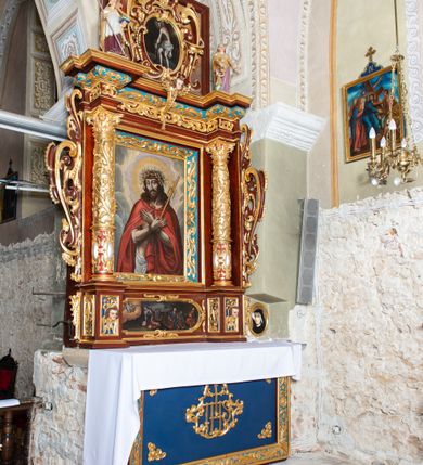 Zdjęcie nr 2: Ołtarz architektoniczny, jednoosiowy, jednokondygnacyjny ze zwieńczeniem. Ołtarz murowany, prostopadłościenny z kamienną mensą. Antepedium drewniane, w polu którego ozdobny, płaskorzeźbiony monogram Chrystusa na niebieskim tle wraz z dekoracją ornamentalną w narożach pola. Pole ujęte ozdobną ramą z płaskorzeźbionym ornamentem z wici roślinnej na jasnoniebieskim tle. Drewniane retabulum ustawione na cokole. W polu obraz z przedstawieniem Modlitwy w Ogrójcu w kształcie leżącego prostokąta o krótszych bokach zakończonych łukiem nadwieszonym. Nastawa flankowana parą kolumn podtrzymujących wyłamane nad osią główną belkowanie. W polu głównym obraz Ecce Homo, a na zasuwie obraz św. Antoniego Padewskiego. Zwieńczenie w formie owalu ujętego ażurową dekoracją formowaną z ornamentu małżowinowo-chrząstkowego na tle kwadratowej ramy. W polu obraz Chrystusa u słupa, po bokach figury, po lewej św. Mikołaja, po prawej św. Doroty, na szczycie figura św. Józefa. Partie cokołów ozdobione płycinami z uskrzydlonymi główkami aniołów w polu, po bokach dekorowane ornamentem małżowinowo-chrząstkowym. Zasadnicza część nastawy ujęta po bokach uszami z ornamentem o formach małżowinowo-chrząstkowych, z czego prawy złożony, dostosowany do południowego filaru kościoła. Trzony kolumn w dolnej partii ozdobione kartuszami o fantazyjnych wycięciach z motywami kaboszonów, w górnej partii pokryte dekoracją w formie wici winnej latorośli. W partii fryzu oraz pod gzymsem ornamentyka roślinna. Pośrodku belkowania motyw dekoracyjnego spływu z uskrzydloną główką aniołka z podwiązaną chustą pod szyją. Pole środkowe w formie prostokątnej wnęki ujętej profilowanymi ramami z czego wewnętrzna ozdobiona ornamentem małżowinowo-chrząstkowym. Polichromia struktury ołtarza utrzymana w odcieniach ciemnego brązu i czerwieni, partie w tle ornamentów niebieskie. Ornamentyka i elementy detalu architektonicznego złocone i srebrzone. 

