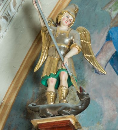 Zdjęcie nr 5: Ołtarz architektoniczny, jednoosiowy, jednokondygnacyjny ze zwieńczeniem. Ołtarz murowany, prostopadłościenny z kamienną mensą. Antepedium drewniane, w polu którego ozdobny, płaskorzeźbiony monogram maryjny na niebieskim tle oraz dekoracja ornamentalna w narożach pola. Pole ujęte ozdobną ramą z płaskorzeźbionym ornamentem z wici roślinnej na jasnoniebieskim tle. Drewniane retabulum ustawione na cokole. W predelli obraz z przedstawieniem Nawiedzenia Najświętszej Marii Panny w kształcie leżącego prostokąta o krótszych bokach zakończonych półkolistym łukiem nadwieszonym. Nastawa flankowana parą kolumn podtrzymujących wyłamane nad osią główną belkowanie. W polu głównym obraz Matki Boskiej Śnieżnej, a na zasuwie obraz Najświętsze Serce Jezusa. Zwieńczenie w formie owalu ujętego dekoracyjną, ażurową ramą formowaną z ornamentu małżowinowo-chrząstkowego na tle kwadratowej ramy. W polu znajduje się obraz „Koronacja Najświętszej Marii Panny”, a po bokach figury, po lewej: św. Archanioła Rafała z Tobiaszem, po prawej: św. Jana Ewangelisty, na szczycie figura św. Michała Archanioła. Partie cokołów ozdobione są ornamentem w formie kartusza o fantazyjnie kształtowanych krawędziach, z motywem kaboszonów pośrodku. Cokoły po zewnętrznej stronie zostały ozdobione ornamentalnym podwieszeniem z motywem małżowinowo-chrząstkowym. Zasadnicza część nastawy ujęta po bokach uszami z ornamentem o formach małżowinowo-chrząstkowych, z czego lewy złożony, dostosowany do północnego filaru kościoła. Trzony kolumn w dolnej partii ozdobione kartuszami o fantazyjnych wycięciach z motywami kaboszonów, w górnej partii pokryte dekoracją w formie wici winnej latorośli. W partii fryzu oraz pod gzymsem ornamentyka roślinna. Pośrodku belkowania motyw dekoracyjnego spływu z uskrzydloną główką aniołka z podwiązaną chustą pod szyją. Pole środkowe w formie prostokątnej wnęki ujętej profilowanymi ramami z czego wewnętrzna ozdobiona ornamentem małżowinowo-chrząstkowym z motywami uskrzydlonych główek aniołków pośrodku każdego boku ramy. Polichromia struktury ołtarza utrzymana w odcieniach ciemnego brązu i bordo, partie w tle ornamentów niebieskie. Ornamentyka i elementy detalu architektonicznego złocone i srebrzone. 