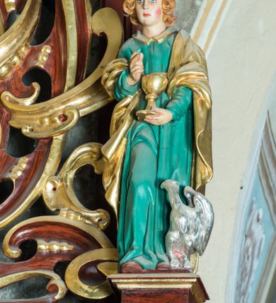 Zdjęcie nr 18: Ołtarz architektoniczny, jednoosiowy, jednokondygnacyjny ze zwieńczeniem. Ołtarz murowany, prostopadłościenny z kamienną mensą. Antepedium drewniane, w polu którego ozdobny, płaskorzeźbiony monogram maryjny na niebieskim tle oraz dekoracja ornamentalna w narożach pola. Pole ujęte ozdobną ramą z płaskorzeźbionym ornamentem z wici roślinnej na jasnoniebieskim tle. Drewniane retabulum ustawione na cokole. W predelli obraz z przedstawieniem Nawiedzenia Najświętszej Marii Panny w kształcie leżącego prostokąta o krótszych bokach zakończonych półkolistym łukiem nadwieszonym. Nastawa flankowana parą kolumn podtrzymujących wyłamane nad osią główną belkowanie. W polu głównym obraz Matki Boskiej Śnieżnej, a na zasuwie obraz Najświętsze Serce Jezusa. Zwieńczenie w formie owalu ujętego dekoracyjną, ażurową ramą formowaną z ornamentu małżowinowo-chrząstkowego na tle kwadratowej ramy. W polu znajduje się obraz „Koronacja Najświętszej Marii Panny”, a po bokach figury, po lewej: św. Archanioła Rafała z Tobiaszem, po prawej: św. Jana Ewangelisty, na szczycie figura św. Michała Archanioła. Partie cokołów ozdobione są ornamentem w formie kartusza o fantazyjnie kształtowanych krawędziach, z motywem kaboszonów pośrodku. Cokoły po zewnętrznej stronie zostały ozdobione ornamentalnym podwieszeniem z motywem małżowinowo-chrząstkowym. Zasadnicza część nastawy ujęta po bokach uszami z ornamentem o formach małżowinowo-chrząstkowych, z czego lewy złożony, dostosowany do północnego filaru kościoła. Trzony kolumn w dolnej partii ozdobione kartuszami o fantazyjnych wycięciach z motywami kaboszonów, w górnej partii pokryte dekoracją w formie wici winnej latorośli. W partii fryzu oraz pod gzymsem ornamentyka roślinna. Pośrodku belkowania motyw dekoracyjnego spływu z uskrzydloną główką aniołka z podwiązaną chustą pod szyją. Pole środkowe w formie prostokątnej wnęki ujętej profilowanymi ramami z czego wewnętrzna ozdobiona ornamentem małżowinowo-chrząstkowym z motywami uskrzydlonych główek aniołków pośrodku każdego boku ramy. Polichromia struktury ołtarza utrzymana w odcieniach ciemnego brązu i bordo, partie w tle ornamentów niebieskie. Ornamentyka i elementy detalu architektonicznego złocone i srebrzone. 