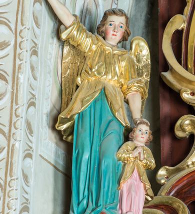 Zdjęcie nr 16: Ołtarz architektoniczny, jednoosiowy, jednokondygnacyjny ze zwieńczeniem. Ołtarz murowany, prostopadłościenny z kamienną mensą. Antepedium drewniane, w polu którego ozdobny, płaskorzeźbiony monogram maryjny na niebieskim tle oraz dekoracja ornamentalna w narożach pola. Pole ujęte ozdobną ramą z płaskorzeźbionym ornamentem z wici roślinnej na jasnoniebieskim tle. Drewniane retabulum ustawione na cokole. W predelli obraz z przedstawieniem Nawiedzenia Najświętszej Marii Panny w kształcie leżącego prostokąta o krótszych bokach zakończonych półkolistym łukiem nadwieszonym. Nastawa flankowana parą kolumn podtrzymujących wyłamane nad osią główną belkowanie. W polu głównym obraz Matki Boskiej Śnieżnej, a na zasuwie obraz Najświętsze Serce Jezusa. Zwieńczenie w formie owalu ujętego dekoracyjną, ażurową ramą formowaną z ornamentu małżowinowo-chrząstkowego na tle kwadratowej ramy. W polu znajduje się obraz „Koronacja Najświętszej Marii Panny”, a po bokach figury, po lewej: św. Archanioła Rafała z Tobiaszem, po prawej: św. Jana Ewangelisty, na szczycie figura św. Michała Archanioła. Partie cokołów ozdobione są ornamentem w formie kartusza o fantazyjnie kształtowanych krawędziach, z motywem kaboszonów pośrodku. Cokoły po zewnętrznej stronie zostały ozdobione ornamentalnym podwieszeniem z motywem małżowinowo-chrząstkowym. Zasadnicza część nastawy ujęta po bokach uszami z ornamentem o formach małżowinowo-chrząstkowych, z czego lewy złożony, dostosowany do północnego filaru kościoła. Trzony kolumn w dolnej partii ozdobione kartuszami o fantazyjnych wycięciach z motywami kaboszonów, w górnej partii pokryte dekoracją w formie wici winnej latorośli. W partii fryzu oraz pod gzymsem ornamentyka roślinna. Pośrodku belkowania motyw dekoracyjnego spływu z uskrzydloną główką aniołka z podwiązaną chustą pod szyją. Pole środkowe w formie prostokątnej wnęki ujętej profilowanymi ramami z czego wewnętrzna ozdobiona ornamentem małżowinowo-chrząstkowym z motywami uskrzydlonych główek aniołków pośrodku każdego boku ramy. Polichromia struktury ołtarza utrzymana w odcieniach ciemnego brązu i bordo, partie w tle ornamentów niebieskie. Ornamentyka i elementy detalu architektonicznego złocone i srebrzone. 