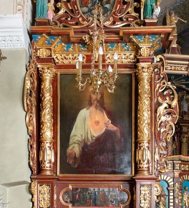 Zdjęcie nr 2: Ołtarz architektoniczny, jednoosiowy, jednokondygnacyjny ze zwieńczeniem. Ołtarz murowany, prostopadłościenny z kamienną mensą. Antepedium drewniane, w polu którego ozdobny, płaskorzeźbiony monogram maryjny na niebieskim tle oraz dekoracja ornamentalna w narożach pola. Pole ujęte ozdobną ramą z płaskorzeźbionym ornamentem z wici roślinnej na jasnoniebieskim tle. Drewniane retabulum ustawione na cokole. W predelli obraz z przedstawieniem Nawiedzenia Najświętszej Marii Panny w kształcie leżącego prostokąta o krótszych bokach zakończonych półkolistym łukiem nadwieszonym. Nastawa flankowana parą kolumn podtrzymujących wyłamane nad osią główną belkowanie. W polu głównym obraz Matki Boskiej Śnieżnej, a na zasuwie obraz Najświętsze Serce Jezusa. Zwieńczenie w formie owalu ujętego dekoracyjną, ażurową ramą formowaną z ornamentu małżowinowo-chrząstkowego na tle kwadratowej ramy. W polu znajduje się obraz „Koronacja Najświętszej Marii Panny”, a po bokach figury, po lewej: św. Archanioła Rafała z Tobiaszem, po prawej: św. Jana Ewangelisty, na szczycie figura św. Michała Archanioła. Partie cokołów ozdobione są ornamentem w formie kartusza o fantazyjnie kształtowanych krawędziach, z motywem kaboszonów pośrodku. Cokoły po zewnętrznej stronie zostały ozdobione ornamentalnym podwieszeniem z motywem małżowinowo-chrząstkowym. Zasadnicza część nastawy ujęta po bokach uszami z ornamentem o formach małżowinowo-chrząstkowych, z czego lewy złożony, dostosowany do północnego filaru kościoła. Trzony kolumn w dolnej partii ozdobione kartuszami o fantazyjnych wycięciach z motywami kaboszonów, w górnej partii pokryte dekoracją w formie wici winnej latorośli. W partii fryzu oraz pod gzymsem ornamentyka roślinna. Pośrodku belkowania motyw dekoracyjnego spływu z uskrzydloną główką aniołka z podwiązaną chustą pod szyją. Pole środkowe w formie prostokątnej wnęki ujętej profilowanymi ramami z czego wewnętrzna ozdobiona ornamentem małżowinowo-chrząstkowym z motywami uskrzydlonych główek aniołków pośrodku każdego boku ramy. Polichromia struktury ołtarza utrzymana w odcieniach ciemnego brązu i bordo, partie w tle ornamentów niebieskie. Ornamentyka i elementy detalu architektonicznego złocone i srebrzone. 