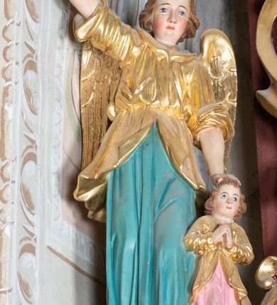 Zdjęcie nr 17: Ołtarz architektoniczny, jednoosiowy, jednokondygnacyjny ze zwieńczeniem. Ołtarz murowany, prostopadłościenny z kamienną mensą. Antepedium drewniane, w polu którego ozdobny, płaskorzeźbiony monogram maryjny na niebieskim tle oraz dekoracja ornamentalna w narożach pola. Pole ujęte ozdobną ramą z płaskorzeźbionym ornamentem z wici roślinnej na jasnoniebieskim tle. Drewniane retabulum ustawione na cokole. W predelli obraz z przedstawieniem Nawiedzenia Najświętszej Marii Panny w kształcie leżącego prostokąta o krótszych bokach zakończonych półkolistym łukiem nadwieszonym. Nastawa flankowana parą kolumn podtrzymujących wyłamane nad osią główną belkowanie. W polu głównym obraz Matki Boskiej Śnieżnej, a na zasuwie obraz Najświętsze Serce Jezusa. Zwieńczenie w formie owalu ujętego dekoracyjną, ażurową ramą formowaną z ornamentu małżowinowo-chrząstkowego na tle kwadratowej ramy. W polu znajduje się obraz „Koronacja Najświętszej Marii Panny”, a po bokach figury, po lewej: św. Archanioła Rafała z Tobiaszem, po prawej: św. Jana Ewangelisty, na szczycie figura św. Michała Archanioła. Partie cokołów ozdobione są ornamentem w formie kartusza o fantazyjnie kształtowanych krawędziach, z motywem kaboszonów pośrodku. Cokoły po zewnętrznej stronie zostały ozdobione ornamentalnym podwieszeniem z motywem małżowinowo-chrząstkowym. Zasadnicza część nastawy ujęta po bokach uszami z ornamentem o formach małżowinowo-chrząstkowych, z czego lewy złożony, dostosowany do północnego filaru kościoła. Trzony kolumn w dolnej partii ozdobione kartuszami o fantazyjnych wycięciach z motywami kaboszonów, w górnej partii pokryte dekoracją w formie wici winnej latorośli. W partii fryzu oraz pod gzymsem ornamentyka roślinna. Pośrodku belkowania motyw dekoracyjnego spływu z uskrzydloną główką aniołka z podwiązaną chustą pod szyją. Pole środkowe w formie prostokątnej wnęki ujętej profilowanymi ramami z czego wewnętrzna ozdobiona ornamentem małżowinowo-chrząstkowym z motywami uskrzydlonych główek aniołków pośrodku każdego boku ramy. Polichromia struktury ołtarza utrzymana w odcieniach ciemnego brązu i bordo, partie w tle ornamentów niebieskie. Ornamentyka i elementy detalu architektonicznego złocone i srebrzone. 