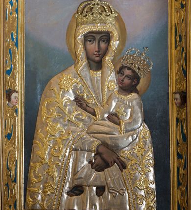Zdjęcie nr 1: Obraz w kształcie stojącego prostokąta z wizerunkiem Matki Boskiej Śnieżnej. Maria przedstawiona frontalnie, w półpostaci, z Dzieciątkiem Jezus na lewym ręku, ze skrzyżowanymi dłońmi. Twarz podłużna, z długim i wąskim nosem, drobnymi ustami, dużymi oczami obwiedzionymi regularnymi łukami brwiowymi, ze wzrokiem skierowanym wprost na widza. Dzieciątko zwrócone trzy czwarte w prawo, w pozycji siedzącej, z książką ze znakiem krzyża na obwolucie w lewej dłoni, prawą czyniące gest błogosławieństwa, na stopach ma namalowane rzymskie sandałki. Twarz okrągła o wyrazistych rysach, duże i brązowe oczy, zarumienione policzki, włosy kręcone, średniej długości opadające na plecy, wzrok skierowany na Matkę. Wokół głów Marii i Dzieciątka złote i koliste nimby. Tło w ciemnych odcieniach szarości i koloru niebieskiego, rozjaśnione w górnej części. Na postacie Marii i Dzieciątka nałożone metalowe: sukienki, korony w typie zamkniętym oraz chustka w dłoni Marii. Sukienki ozdobione wicią roślinną z kwiatami.




