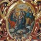 Zdjęcie nr 1: Obraz w kształcie owalu przedstawiający koronację Najświętszej Marii Panny. Pośrodku klęcząca Maria, delikatnie zwrócona w lewo, z rękami skrzyżowanymi na piersiach, z głową zwróconą w prawo. Ma szeroką twarz z wysokim czołem, z małymi ustami, długim nosem i delikatnie przymkniętymi oczami oraz silnie zarumienione policzki. Ubrana jest w długą i różową suknię z długimi rękawami, niebieski płaszcz z jasnobłękitną podszewką oraz jasnobrązowy welon, spod którego widać ciemnobrązowe włosy. Po prawej stronie obrazu znajduje się siedzący Bóg Ojciec, prawą ręką trzymający koronę nad głową Marii, z lewą ręką wspartą na niebieskim globie ziemskim. Twarz o rysach starszego mężczyzny, okolona długą i siwą brodą oraz długimi i siwymi włosami. Ubrany jest w niebieską długą suknię z długimi rękawami oraz złoty płaszcz z zieloną podszewką spięty na piersiach, na brzegach zdobiony perełkowaniem. Po lewej stronie Chrystus ukazany w pozycji siedzącej, zwrócony w lewo, prawą ręką podtrzymujący koronę nad głową Marii, w lewej dzierżący długie berło. Twarz widoczna z prawego profilu, okolona krótką i brązową brodą oraz długimi, falującymi włosami, spływającymi na plecy. Ubrany jest w niebieską szatę, odsłaniającą nagi tors oraz czerwony płaszcz. Wszystkie postacie mają wokół głów białe i koliste nimby. W dolnej części kompozycji na tle bujnych chmur znajdują się uskrzydlone główki aniołków; w górnej części obrazu gołębica Ducha Świętego z rozpostartymi szeroko skrzydłami, od której odchodzą promienie światła, a wokół niej biała, owalna aureola na tle żółtego nieba. 



