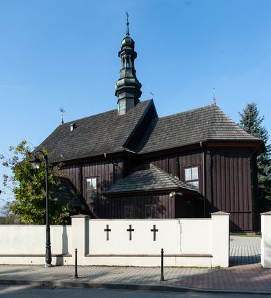 Zdjęcie nr 2: Kościół orientowany, jednonawowy, z węższym, zamkniętym wielobocznie prezbiterium, przy którym od północy prostokątna zakrystia (obecnie skarbiec) od południa prostokątna nowa zakrystia. Przy korpusie od południa i zachodu kruchty. Wewnątrz stropy, w prezbiterium i środkowej części nawy z fasetami; w nawie boczne płaskie odcinki stropu wparte na dwóch słupach. W prezbiterium i nawie na stropach dekoracja geometryczna z listew. Ściany artykułowane pilastrami. Tęcza o wystroju prostokątnym, ujęta przyściennymi filarami. Zewnątrz ściany szalowane deskowaniem na nakładkę, opięte pilastrami. Fasada rozczłonkowana czterema pilastrami wspierającymi gzyms, pośrodku wyłamany nad oknem wchodzącym w pole szczytu. Szczyt trójkątny, w połowie przedzielony gzymsem. Dachy dwuspadowe, nad prezbiterium wielopołaciowy, nad nową zakrystią namiotowy oraz pulpitowe; na kalenicy dachu nawy sygnaturka. Okna prostokątne w profilowanych obramieniach. Portal uszaty, z datą: 1748.