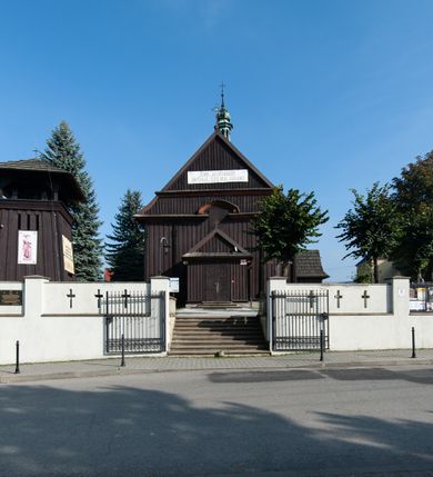 Zdjęcie nr 3: Kościół orientowany, jednonawowy, z węższym, zamkniętym wielobocznie prezbiterium, przy którym od północy prostokątna zakrystia (obecnie skarbiec) od południa prostokątna nowa zakrystia. Przy korpusie od południa i zachodu kruchty. Wewnątrz stropy, w prezbiterium i środkowej części nawy z fasetami; w nawie boczne płaskie odcinki stropu wparte na dwóch słupach. W prezbiterium i nawie na stropach dekoracja geometryczna z listew. Ściany artykułowane pilastrami. Tęcza o wystroju prostokątnym, ujęta przyściennymi filarami. Zewnątrz ściany szalowane deskowaniem na nakładkę, opięte pilastrami. Fasada rozczłonkowana czterema pilastrami wspierającymi gzyms, pośrodku wyłamany nad oknem wchodzącym w pole szczytu. Szczyt trójkątny, w połowie przedzielony gzymsem. Dachy dwuspadowe, nad prezbiterium wielopołaciowy, nad nową zakrystią namiotowy oraz pulpitowe; na kalenicy dachu nawy sygnaturka. Okna prostokątne w profilowanych obramieniach. Portal uszaty, z datą: 1748.