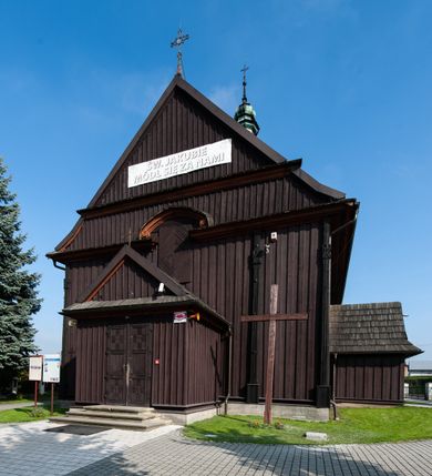 Zdjęcie nr 8: Kościół orientowany, jednonawowy, z węższym, zamkniętym wielobocznie prezbiterium, przy którym od północy prostokątna zakrystia (obecnie skarbiec) od południa prostokątna nowa zakrystia. Przy korpusie od południa i zachodu kruchty. Wewnątrz stropy, w prezbiterium i środkowej części nawy z fasetami; w nawie boczne płaskie odcinki stropu wparte na dwóch słupach. W prezbiterium i nawie na stropach dekoracja geometryczna z listew. Ściany artykułowane pilastrami. Tęcza o wystroju prostokątnym, ujęta przyściennymi filarami. Zewnątrz ściany szalowane deskowaniem na nakładkę, opięte pilastrami. Fasada rozczłonkowana czterema pilastrami wspierającymi gzyms, pośrodku wyłamany nad oknem wchodzącym w pole szczytu. Szczyt trójkątny, w połowie przedzielony gzymsem. Dachy dwuspadowe, nad prezbiterium wielopołaciowy, nad nową zakrystią namiotowy oraz pulpitowe; na kalenicy dachu nawy sygnaturka. Okna prostokątne w profilowanych obramieniach. Portal uszaty, z datą: 1748.