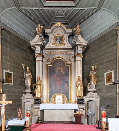 Zdjęcie nr 17: Kościół orientowany, jednonawowy, z węższym, zamkniętym wielobocznie prezbiterium, przy którym od północy prostokątna zakrystia (obecnie skarbiec) od południa prostokątna nowa zakrystia. Przy korpusie od południa i zachodu kruchty. Wewnątrz stropy, w prezbiterium i środkowej części nawy z fasetami; w nawie boczne płaskie odcinki stropu wparte na dwóch słupach. W prezbiterium i nawie na stropach dekoracja geometryczna z listew. Ściany artykułowane pilastrami. Tęcza o wystroju prostokątnym, ujęta przyściennymi filarami. Zewnątrz ściany szalowane deskowaniem na nakładkę, opięte pilastrami. Fasada rozczłonkowana czterema pilastrami wspierającymi gzyms, pośrodku wyłamany nad oknem wchodzącym w pole szczytu. Szczyt trójkątny, w połowie przedzielony gzymsem. Dachy dwuspadowe, nad prezbiterium wielopołaciowy, nad nową zakrystią namiotowy oraz pulpitowe; na kalenicy dachu nawy sygnaturka. Okna prostokątne w profilowanych obramieniach. Portal uszaty, z datą: 1748.