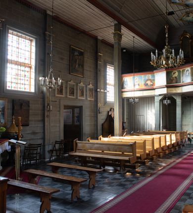 Zdjęcie nr 28: Kościół orientowany, jednonawowy, z węższym, zamkniętym wielobocznie prezbiterium, przy którym od północy prostokątna zakrystia (obecnie skarbiec) od południa prostokątna nowa zakrystia. Przy korpusie od południa i zachodu kruchty. Wewnątrz stropy, w prezbiterium i środkowej części nawy z fasetami; w nawie boczne płaskie odcinki stropu wparte na dwóch słupach. W prezbiterium i nawie na stropach dekoracja geometryczna z listew. Ściany artykułowane pilastrami. Tęcza o wystroju prostokątnym, ujęta przyściennymi filarami. Zewnątrz ściany szalowane deskowaniem na nakładkę, opięte pilastrami. Fasada rozczłonkowana czterema pilastrami wspierającymi gzyms, pośrodku wyłamany nad oknem wchodzącym w pole szczytu. Szczyt trójkątny, w połowie przedzielony gzymsem. Dachy dwuspadowe, nad prezbiterium wielopołaciowy, nad nową zakrystią namiotowy oraz pulpitowe; na kalenicy dachu nawy sygnaturka. Okna prostokątne w profilowanych obramieniach. Portal uszaty, z datą: 1748.