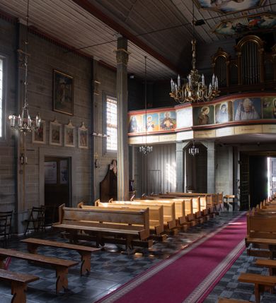 Zdjęcie nr 30: Kościół orientowany, jednonawowy, z węższym, zamkniętym wielobocznie prezbiterium, przy którym od północy prostokątna zakrystia (obecnie skarbiec) od południa prostokątna nowa zakrystia. Przy korpusie od południa i zachodu kruchty. Wewnątrz stropy, w prezbiterium i środkowej części nawy z fasetami; w nawie boczne płaskie odcinki stropu wparte na dwóch słupach. W prezbiterium i nawie na stropach dekoracja geometryczna z listew. Ściany artykułowane pilastrami. Tęcza o wystroju prostokątnym, ujęta przyściennymi filarami. Zewnątrz ściany szalowane deskowaniem na nakładkę, opięte pilastrami. Fasada rozczłonkowana czterema pilastrami wspierającymi gzyms, pośrodku wyłamany nad oknem wchodzącym w pole szczytu. Szczyt trójkątny, w połowie przedzielony gzymsem. Dachy dwuspadowe, nad prezbiterium wielopołaciowy, nad nową zakrystią namiotowy oraz pulpitowe; na kalenicy dachu nawy sygnaturka. Okna prostokątne w profilowanych obramieniach. Portal uszaty, z datą: 1748.