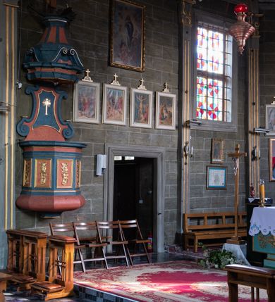 Zdjęcie nr 29: Kościół orientowany, jednonawowy, z węższym, zamkniętym wielobocznie prezbiterium, przy którym od północy prostokątna zakrystia (obecnie skarbiec) od południa prostokątna nowa zakrystia. Przy korpusie od południa i zachodu kruchty. Wewnątrz stropy, w prezbiterium i środkowej części nawy z fasetami; w nawie boczne płaskie odcinki stropu wparte na dwóch słupach. W prezbiterium i nawie na stropach dekoracja geometryczna z listew. Ściany artykułowane pilastrami. Tęcza o wystroju prostokątnym, ujęta przyściennymi filarami. Zewnątrz ściany szalowane deskowaniem na nakładkę, opięte pilastrami. Fasada rozczłonkowana czterema pilastrami wspierającymi gzyms, pośrodku wyłamany nad oknem wchodzącym w pole szczytu. Szczyt trójkątny, w połowie przedzielony gzymsem. Dachy dwuspadowe, nad prezbiterium wielopołaciowy, nad nową zakrystią namiotowy oraz pulpitowe; na kalenicy dachu nawy sygnaturka. Okna prostokątne w profilowanych obramieniach. Portal uszaty, z datą: 1748.