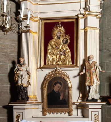 Zdjęcie nr 1: Ołtarz jednoosiowy, jednokondygnacyjny, ze zwieńczeniem. Mensa umieszczona na tumbie zwężającej się ku dołowi, ozdobionej od czoła płyciną prostokątną w złoconym obramieniu, pośrodku ze splecionymi literami imienia Maria. Nastawa flankowana ustawionymi ukośnie czworobocznymi, kanelowanymi filarami, dźwigającymi odcinki pełnego belkowania i gzymsu, przerwanych nad polem środkowym. Na tle filarów umieszczone na konsolach rzeźby: św. Stanisława Kostki (po lewej) i św. Ignacego Loyoli (po prawej). W polu środkowym, nad mensą zawieszony obraz w ozdobnej ramie z przedstawieniem św. Stanisława Kostki w półpostaci; wyżej prostokątna nisza, w której obraz Matki Boskiej z Dzieciątkiem. Zwieńczenie w kształcie aediculi zamkniętej łukiem półkolistym nadwieszonym, w której polu obraz z przedstawieniem św. Józefa w półpostaci. Po bokach, w osiach filarów odcinki przerwanego przyczółka na których rzeźby nagich, uskrzydlonych puttów.  Na gzymsie wieńczącym ołtarz Gołębica Ducha Świętego wśród promieni.