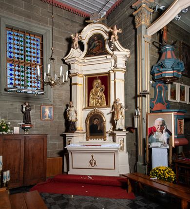 Zdjęcie nr 3: Ołtarz jednoosiowy, jednokondygnacyjny, ze zwieńczeniem. Mensa umieszczona na tumbie zwężającej się ku dołowi, ozdobionej od czoła płyciną prostokątną w złoconym obramieniu, pośrodku ze splecionymi literami imienia Maria. Nastawa flankowana ustawionymi ukośnie czworobocznymi, kanelowanymi filarami, dźwigającymi odcinki pełnego belkowania i gzymsu, przerwanych nad polem środkowym. Na tle filarów umieszczone na konsolach rzeźby: św. Stanisława Kostki (po lewej) i św. Ignacego Loyoli (po prawej). W polu środkowym, nad mensą zawieszony obraz w ozdobnej ramie z przedstawieniem św. Stanisława Kostki w półpostaci; wyżej prostokątna nisza, w której obraz Matki Boskiej z Dzieciątkiem. Zwieńczenie w kształcie aediculi zamkniętej łukiem półkolistym nadwieszonym, w której polu obraz z przedstawieniem św. Józefa w półpostaci. Po bokach, w osiach filarów odcinki przerwanego przyczółka na których rzeźby nagich, uskrzydlonych puttów.  Na gzymsie wieńczącym ołtarz Gołębica Ducha Świętego wśród promieni.