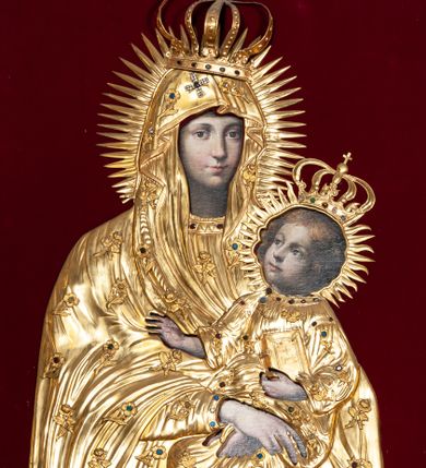 Zdjęcie nr 1: Przedstawienie Matki Boskiej z Dzieciątkiem w typie Matki Boskiej Śnieżnej. Twarz Marii, głowa i stopy Dzieciątka oraz dłonie malowane; szaty Marii i Dzieciątka promieniste nimby wokół głów oraz zamknięte korony wykonane z trybowanej złoconej blachy, ozdobione motywami kwiatów i kameryzacją. Tło z czerwonego aksamitu.