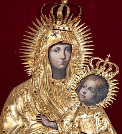 Zdjęcie nr 6: Przedstawienie Matki Boskiej z Dzieciątkiem w typie Matki Boskiej Śnieżnej. Twarz Marii, głowa i stopy Dzieciątka oraz dłonie malowane; szaty Marii i Dzieciątka promieniste nimby wokół głów oraz zamknięte korony wykonane z trybowanej złoconej blachy, ozdobione motywami kwiatów i kameryzacją. Tło z czerwonego aksamitu.