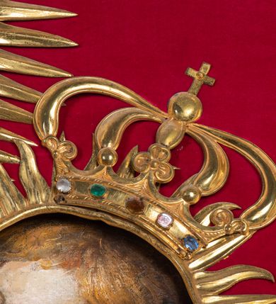 Zdjęcie nr 11: Przedstawienie Matki Boskiej z Dzieciątkiem w typie Matki Boskiej Śnieżnej. Twarz Marii, głowa i stopy Dzieciątka oraz dłonie malowane; szaty Marii i Dzieciątka promieniste nimby wokół głów oraz zamknięte korony wykonane z trybowanej złoconej blachy, ozdobione motywami kwiatów i kameryzacją. Tło z czerwonego aksamitu.