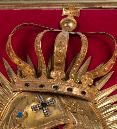 Zdjęcie nr 12: Przedstawienie Matki Boskiej z Dzieciątkiem w typie Matki Boskiej Śnieżnej. Twarz Marii, głowa i stopy Dzieciątka oraz dłonie malowane; szaty Marii i Dzieciątka promieniste nimby wokół głów oraz zamknięte korony wykonane z trybowanej złoconej blachy, ozdobione motywami kwiatów i kameryzacją. Tło z czerwonego aksamitu.