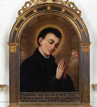 Zdjęcie nr 2: Obraz w kształcie prostokąta zamkniętego półkoliście z przedstawieniem św. Stanisława Kostki. Święty ukazany w półpostaci, zwrócony w trzech czwartych w lewo, z pochyloną głową, rękami zgiętymi w łokciach i dłońmi złożonymi do modlitwy na wysokości piersi. Twarz młodzieńcza, o jasnej karnacji. Ubrany w czarną sutannę jezuicką. Tło monochromatyczne, rozświetlone za głową świętego. U dołu obrazu napis czarną kapitałą na jasnym tle: S STANISLAUS KOSTKA SOCIETATIS IESU / PATRONUS HUIUS PAROCHIE QUAM(QUE) PESTE / HOMINUM ANNO 1678 LIBERAVIT. Obraz w drewnianej złoconej ramie w kształcie półkolistej arkady z kanelowanymi pilastrami, nadwieszonymi na konsolkach, z ażurowym fryzem arkadkowym u dołu. 