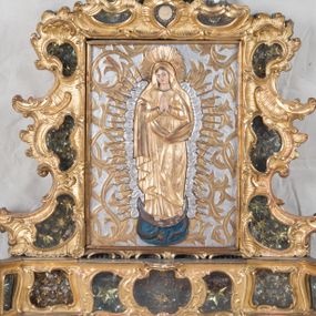 Zdjęcie nr 1: Feretron dwustronny z płaskorzeźbą Najświętszej Marii Panny Niepokalanie Poczętej na awersie oraz płaskorzeźbą ze sceną Narodzenia Najświętszej Marii Panny na rewersie, ustawiony na niskim postumencie o fantazyjnym wykroju z osią główną wysuniętą do przodu oraz narożnikami ustawionymi ukośnie. W postumencie dziewięć przeszklonych gablotek mieszczących relikwie świętych, które opisane są na małych karteczkach, otoczone różnego rodzaju kwiatkami  i gwiazdkami wykonanymi z papieru i cienkich blaszek. Otwory gablotek  o różnorodnym, fantazyjnym, opływowym wykroju. Na górnej powierzchni podstawy, po bokach małe otwory po zatkniętych w nich, niezachowanych rzeźbach apostołów. Rama obrazów w kształcie stojącego prostokąta, ujęta po każdej stronie trzema gablotkami otoczonymi rzeźbionym ornamentem rocaille'owym. W zwieńczeniu takie same, mniejsze gablotki, pośrodku zamiast relikwii owalna plakietka z kości z przedstawieniem Ucieczki do Egiptu. W zwieńczeniu na obłokach dwa aniołki podtrzymujące koronę. Na rewersie struktura feretronu o takim samym kształcie. Podstawa zdobiona gęstą wicią ze stylizowanych liści akantu zamkniętą w kształcie prostokąta leżącego.  Po bokach zamiast gablotek owoidalne pola, w których znajduje się złocona, drobna kratka.  W zwieńczeniu, w polu środkowym monogram Marii, powyżej aniołki trzymające koronę widoczne od tyłu.

Na awersie płaskorzeźba z przedstawieniem Najświętszej Marii Panny Niepokalanie Poczętej. Maria ukazana w postawie stojącej, frontalnie, na półksiężycu  i globie ziemskim, depcząca bosymi stopami węża, ze złożonymi w geście modlitwy rękami, z głową delikatnie przechyloną w prawą stronę. Twarz owalna z małymi i wąskimi ustami, wzrokiem skierowanym w dal. Włosy jasnobrązowe z przedziałkiem pośrodku, skryte pod płaszczem. Ubrana w długą, złoconą suknię z długimi rękawami, przewiązaną pod biustem oraz złoty płaszcz założony  na głowę i otulający całą postać, z lewym końcem przerzuconym przez prawe przedramię. W dolnej partii płaszcza oraz na prawej piersi ryta dekoracja roślinna, składająca się z sześciu ulistnionych gałązek z pięcio- lub sześciopłatkowymi kwiatkami. Wokół całej postaci Marii otok z srebrnych obłoków oraz promieni naprzemiennie prostych  i falujących. Wokół głowy złoty, kolisty nimb z gęsto ułożonych promieni; na nim okrąg z gwiazd dwunastu, częściowo nie zachowany. Tło srebrne, zdobione złoconą  i płaskorzeźbioną wicią z liści stylizujących suchy akant.

Na rewersie płaskorzeźba z przedstawieniem Narodzenia Najświętszej Marii Panny. Kompozycja dwustrefowa, w dolnej partii ukazani św. Joachim i św. Anna, w górnej Bóg Ojciec i Matka Boska w otoczeniu uskrzydlonych główek anielskich. Rodzice Marii w pozycji klęczącej, zwróceni trzy czwarte  ku środkowi. Ubrani w długie i złocone suknie z długimi rękawami oraz złote płaszcze, św. Anna z welonem na głowie. Pomiędzy nimi ustawiona ukośnie kołyska, ozdobiona na narożu uskrzydloną główką aniołka, przykryta długą tkaniną. U nóg św. Anny zamknięta księga, na obwolucie zdobiona prostym, łacińskim krzyżykiem. Po prawej stronie obrazu, za św. Anną, na wysokim postumencie antykizujący dzban. W górnej partii kompozycji Bóg Ojciec widoczny w półpostaci, frontalnie,  w lewym ręku trzymający jabłko królewskie, prawą wyciągający ku Marii. Ubrany  w złotą szatę z długimi rękawami oraz złoty płaszcz z rozwianym jednym końcem  po jego prawej stronie, wokół głowy złoty i trójkątny nimb. Twarz okolona gęstą i siwą brodą oraz siwymi, średniej długości włosami. Maria ukazana poniżej Boga Ojca,  w młodzieńczym wieku, w postawie stojącej na półksiężycu, frontalnie, z rękami złożonymi w geście modlitwy. Ubrana w długą i złotą suknię z długimi rękawami oraz złoty płaszcz, którego koniec przerzucony przez lewe ramię; wokół głowy złoty okrągły nimb. Włosy długie i jasnobrązowe, opadające na plecy. Tło utworzone  z obłoków. Wokół Boga Ojca i Marii cztery uskrzydlone główki aniołków o wyraźnie zaznaczonych pucułowatych policzkach. 

Relikwie  świętych umieszczone w niewielkich gablotkach za szybkami, opisane na karteczkach. Zwieńczenie feretronu, od lewej: nierozpoznane relikwie świętego, plakietka z kości  z przedstawieniem Ucieczki do Egiptu, relikwie „Sancta THERESIA Virgo”  Prawy bok feretronu, od góry: relikwie „Sanctae Katarzyny Panny”, relikwie „Sanctae Rozalii Panny”, relikwie „Sancta Illuminata Martir”. Podstawa feretronu, od lewej: relikwie „Sanctus Benedicti Martyr, Sancta Victoria Virgo Martyr, Sancti Floryana Męczennika”; relikwie „Sanctae Marciana Virgo Martyr”; relikwie  „Sanctus Quirini Martir”; relikwie „Sancti Jucundina Martyr”; relikwie „Sanctus Mansueti M.,  Sancta Eugenia Virgo Martyr, Sanctae Bronisławy”. Lewy bok feretronu, od góry: relikwie „Sanctus Jana Kantego”, relikwie „Sanctae Honorati Martyr”, relikwie „Sancta Illuminata Martir”. Plakietka ze sceną ucieczki do Egiptu o kształcie owalnym. W centrum kompozycji ukazani św. Józef oraz Maria z Dzieciątkiem Jezus na osiołku. Wokół słabo czytelny napis: „Cetur doms(e) in aeg vivo[?].” Rzeźby aniołków w zwieńczeniu usytuowane przeciwstawnie, diagonalnie, zwrócone górną partią ciała ku środkowi, jedną ręką podtrzymujące koronę. Ubrane w wąską tkaninę przerzuconą przez jedno z ramion i zwiewnie opadającą w dół. Korona w typie zamkniętym. Struktura feretronu złocona i srebrzona.	