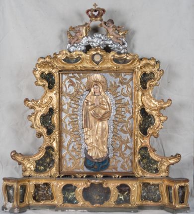 Zdjęcie nr 2: Feretron dwustronny z płaskorzeźbą Najświętszej Marii Panny Niepokalanie Poczętej na awersie oraz płaskorzeźbą ze sceną Narodzenia Najświętszej Marii Panny na rewersie, ustawiony na niskim postumencie o fantazyjnym wykroju z osią główną wysuniętą do przodu oraz narożnikami ustawionymi ukośnie. W postumencie dziewięć przeszklonych gablotek mieszczących relikwie świętych, które opisane są na małych karteczkach, otoczone różnego rodzaju kwiatkami  i gwiazdkami wykonanymi z papieru i cienkich blaszek. Otwory gablotek  o różnorodnym, fantazyjnym, opływowym wykroju. Na górnej powierzchni podstawy, po bokach małe otwory po zatkniętych w nich, niezachowanych rzeźbach apostołów. Rama obrazów w kształcie stojącego prostokąta, ujęta po każdej stronie trzema gablotkami otoczonymi rzeźbionym ornamentem rocaille'owym. W zwieńczeniu takie same, mniejsze gablotki, pośrodku zamiast relikwii owalna plakietka z kości z przedstawieniem Ucieczki do Egiptu. W zwieńczeniu na obłokach dwa aniołki podtrzymujące koronę. Na rewersie struktura feretronu o takim samym kształcie. Podstawa zdobiona gęstą wicią ze stylizowanych liści akantu zamkniętą w kształcie prostokąta leżącego.  Po bokach zamiast gablotek owoidalne pola, w których znajduje się złocona, drobna kratka.  W zwieńczeniu, w polu środkowym monogram Marii, powyżej aniołki trzymające koronę widoczne od tyłu.

Na awersie płaskorzeźba z przedstawieniem Najświętszej Marii Panny Niepokalanie Poczętej. Maria ukazana w postawie stojącej, frontalnie, na półksiężycu  i globie ziemskim, depcząca bosymi stopami węża, ze złożonymi w geście modlitwy rękami, z głową delikatnie przechyloną w prawą stronę. Twarz owalna z małymi i wąskimi ustami, wzrokiem skierowanym w dal. Włosy jasnobrązowe z przedziałkiem pośrodku, skryte pod płaszczem. Ubrana w długą, złoconą suknię z długimi rękawami, przewiązaną pod biustem oraz złoty płaszcz założony  na głowę i otulający całą postać, z lewym końcem przerzuconym przez prawe przedramię. W dolnej partii płaszcza oraz na prawej piersi ryta dekoracja roślinna, składająca się z sześciu ulistnionych gałązek z pięcio- lub sześciopłatkowymi kwiatkami. Wokół całej postaci Marii otok z srebrnych obłoków oraz promieni naprzemiennie prostych  i falujących. Wokół głowy złoty, kolisty nimb z gęsto ułożonych promieni; na nim okrąg z gwiazd dwunastu, częściowo nie zachowany. Tło srebrne, zdobione złoconą  i płaskorzeźbioną wicią z liści stylizujących suchy akant.

Na rewersie płaskorzeźba z przedstawieniem Narodzenia Najświętszej Marii Panny. Kompozycja dwustrefowa, w dolnej partii ukazani św. Joachim i św. Anna, w górnej Bóg Ojciec i Matka Boska w otoczeniu uskrzydlonych główek anielskich. Rodzice Marii w pozycji klęczącej, zwróceni trzy czwarte  ku środkowi. Ubrani w długie i złocone suknie z długimi rękawami oraz złote płaszcze, św. Anna z welonem na głowie. Pomiędzy nimi ustawiona ukośnie kołyska, ozdobiona na narożu uskrzydloną główką aniołka, przykryta długą tkaniną. U nóg św. Anny zamknięta księga, na obwolucie zdobiona prostym, łacińskim krzyżykiem. Po prawej stronie obrazu, za św. Anną, na wysokim postumencie antykizujący dzban. W górnej partii kompozycji Bóg Ojciec widoczny w półpostaci, frontalnie,  w lewym ręku trzymający jabłko królewskie, prawą wyciągający ku Marii. Ubrany  w złotą szatę z długimi rękawami oraz złoty płaszcz z rozwianym jednym końcem  po jego prawej stronie, wokół głowy złoty i trójkątny nimb. Twarz okolona gęstą i siwą brodą oraz siwymi, średniej długości włosami. Maria ukazana poniżej Boga Ojca,  w młodzieńczym wieku, w postawie stojącej na półksiężycu, frontalnie, z rękami złożonymi w geście modlitwy. Ubrana w długą i złotą suknię z długimi rękawami oraz złoty płaszcz, którego koniec przerzucony przez lewe ramię; wokół głowy złoty okrągły nimb. Włosy długie i jasnobrązowe, opadające na plecy. Tło utworzone  z obłoków. Wokół Boga Ojca i Marii cztery uskrzydlone główki aniołków o wyraźnie zaznaczonych pucułowatych policzkach. 

Relikwie  świętych umieszczone w niewielkich gablotkach za szybkami, opisane na karteczkach. Zwieńczenie feretronu, od lewej: nierozpoznane relikwie świętego, plakietka z kości  z przedstawieniem Ucieczki do Egiptu, relikwie „Sancta THERESIA Virgo”  Prawy bok feretronu, od góry: relikwie „Sanctae Katarzyny Panny”, relikwie „Sanctae Rozalii Panny”, relikwie „Sancta Illuminata Martir”. Podstawa feretronu, od lewej: relikwie „Sanctus Benedicti Martyr, Sancta Victoria Virgo Martyr, Sancti Floryana Męczennika”; relikwie „Sanctae Marciana Virgo Martyr”; relikwie  „Sanctus Quirini Martir”; relikwie „Sancti Jucundina Martyr”; relikwie „Sanctus Mansueti M.,  Sancta Eugenia Virgo Martyr, Sanctae Bronisławy”. Lewy bok feretronu, od góry: relikwie „Sanctus Jana Kantego”, relikwie „Sanctae Honorati Martyr”, relikwie „Sancta Illuminata Martir”. Plakietka ze sceną ucieczki do Egiptu o kształcie owalnym. W centrum kompozycji ukazani św. Józef oraz Maria z Dzieciątkiem Jezus na osiołku. Wokół słabo czytelny napis: „Cetur doms(e) in aeg vivo[?].” Rzeźby aniołków w zwieńczeniu usytuowane przeciwstawnie, diagonalnie, zwrócone górną partią ciała ku środkowi, jedną ręką podtrzymujące koronę. Ubrane w wąską tkaninę przerzuconą przez jedno z ramion i zwiewnie opadającą w dół. Korona w typie zamkniętym. Struktura feretronu złocona i srebrzona.	