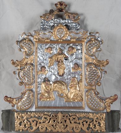 Zdjęcie nr 21: Feretron dwustronny z płaskorzeźbą Najświętszej Marii Panny Niepokalanie Poczętej na awersie oraz płaskorzeźbą ze sceną Narodzenia Najświętszej Marii Panny na rewersie, ustawiony na niskim postumencie o fantazyjnym wykroju z osią główną wysuniętą do przodu oraz narożnikami ustawionymi ukośnie. W postumencie dziewięć przeszklonych gablotek mieszczących relikwie świętych, które opisane są na małych karteczkach, otoczone różnego rodzaju kwiatkami  i gwiazdkami wykonanymi z papieru i cienkich blaszek. Otwory gablotek  o różnorodnym, fantazyjnym, opływowym wykroju. Na górnej powierzchni podstawy, po bokach małe otwory po zatkniętych w nich, niezachowanych rzeźbach apostołów. Rama obrazów w kształcie stojącego prostokąta, ujęta po każdej stronie trzema gablotkami otoczonymi rzeźbionym ornamentem rocaille'owym. W zwieńczeniu takie same, mniejsze gablotki, pośrodku zamiast relikwii owalna plakietka z kości z przedstawieniem Ucieczki do Egiptu. W zwieńczeniu na obłokach dwa aniołki podtrzymujące koronę. Na rewersie struktura feretronu o takim samym kształcie. Podstawa zdobiona gęstą wicią ze stylizowanych liści akantu zamkniętą w kształcie prostokąta leżącego.  Po bokach zamiast gablotek owoidalne pola, w których znajduje się złocona, drobna kratka.  W zwieńczeniu, w polu środkowym monogram Marii, powyżej aniołki trzymające koronę widoczne od tyłu.

Na awersie płaskorzeźba z przedstawieniem Najświętszej Marii Panny Niepokalanie Poczętej. Maria ukazana w postawie stojącej, frontalnie, na półksiężycu  i globie ziemskim, depcząca bosymi stopami węża, ze złożonymi w geście modlitwy rękami, z głową delikatnie przechyloną w prawą stronę. Twarz owalna z małymi i wąskimi ustami, wzrokiem skierowanym w dal. Włosy jasnobrązowe z przedziałkiem pośrodku, skryte pod płaszczem. Ubrana w długą, złoconą suknię z długimi rękawami, przewiązaną pod biustem oraz złoty płaszcz założony  na głowę i otulający całą postać, z lewym końcem przerzuconym przez prawe przedramię. W dolnej partii płaszcza oraz na prawej piersi ryta dekoracja roślinna, składająca się z sześciu ulistnionych gałązek z pięcio- lub sześciopłatkowymi kwiatkami. Wokół całej postaci Marii otok z srebrnych obłoków oraz promieni naprzemiennie prostych  i falujących. Wokół głowy złoty, kolisty nimb z gęsto ułożonych promieni; na nim okrąg z gwiazd dwunastu, częściowo nie zachowany. Tło srebrne, zdobione złoconą  i płaskorzeźbioną wicią z liści stylizujących suchy akant.

Na rewersie płaskorzeźba z przedstawieniem Narodzenia Najświętszej Marii Panny. Kompozycja dwustrefowa, w dolnej partii ukazani św. Joachim i św. Anna, w górnej Bóg Ojciec i Matka Boska w otoczeniu uskrzydlonych główek anielskich. Rodzice Marii w pozycji klęczącej, zwróceni trzy czwarte  ku środkowi. Ubrani w długie i złocone suknie z długimi rękawami oraz złote płaszcze, św. Anna z welonem na głowie. Pomiędzy nimi ustawiona ukośnie kołyska, ozdobiona na narożu uskrzydloną główką aniołka, przykryta długą tkaniną. U nóg św. Anny zamknięta księga, na obwolucie zdobiona prostym, łacińskim krzyżykiem. Po prawej stronie obrazu, za św. Anną, na wysokim postumencie antykizujący dzban. W górnej partii kompozycji Bóg Ojciec widoczny w półpostaci, frontalnie,  w lewym ręku trzymający jabłko królewskie, prawą wyciągający ku Marii. Ubrany  w złotą szatę z długimi rękawami oraz złoty płaszcz z rozwianym jednym końcem  po jego prawej stronie, wokół głowy złoty i trójkątny nimb. Twarz okolona gęstą i siwą brodą oraz siwymi, średniej długości włosami. Maria ukazana poniżej Boga Ojca,  w młodzieńczym wieku, w postawie stojącej na półksiężycu, frontalnie, z rękami złożonymi w geście modlitwy. Ubrana w długą i złotą suknię z długimi rękawami oraz złoty płaszcz, którego koniec przerzucony przez lewe ramię; wokół głowy złoty okrągły nimb. Włosy długie i jasnobrązowe, opadające na plecy. Tło utworzone  z obłoków. Wokół Boga Ojca i Marii cztery uskrzydlone główki aniołków o wyraźnie zaznaczonych pucułowatych policzkach. 

Relikwie  świętych umieszczone w niewielkich gablotkach za szybkami, opisane na karteczkach. Zwieńczenie feretronu, od lewej: nierozpoznane relikwie świętego, plakietka z kości  z przedstawieniem Ucieczki do Egiptu, relikwie „Sancta THERESIA Virgo”  Prawy bok feretronu, od góry: relikwie „Sanctae Katarzyny Panny”, relikwie „Sanctae Rozalii Panny”, relikwie „Sancta Illuminata Martir”. Podstawa feretronu, od lewej: relikwie „Sanctus Benedicti Martyr, Sancta Victoria Virgo Martyr, Sancti Floryana Męczennika”; relikwie „Sanctae Marciana Virgo Martyr”; relikwie  „Sanctus Quirini Martir”; relikwie „Sancti Jucundina Martyr”; relikwie „Sanctus Mansueti M.,  Sancta Eugenia Virgo Martyr, Sanctae Bronisławy”. Lewy bok feretronu, od góry: relikwie „Sanctus Jana Kantego”, relikwie „Sanctae Honorati Martyr”, relikwie „Sancta Illuminata Martir”. Plakietka ze sceną ucieczki do Egiptu o kształcie owalnym. W centrum kompozycji ukazani św. Józef oraz Maria z Dzieciątkiem Jezus na osiołku. Wokół słabo czytelny napis: „Cetur doms(e) in aeg vivo[?].” Rzeźby aniołków w zwieńczeniu usytuowane przeciwstawnie, diagonalnie, zwrócone górną partią ciała ku środkowi, jedną ręką podtrzymujące koronę. Ubrane w wąską tkaninę przerzuconą przez jedno z ramion i zwiewnie opadającą w dół. Korona w typie zamkniętym. Struktura feretronu złocona i srebrzona.	