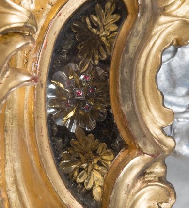 Zdjęcie nr 8: Feretron dwustronny z płaskorzeźbą Najświętszej Marii Panny Niepokalanie Poczętej na awersie oraz płaskorzeźbą ze sceną Narodzenia Najświętszej Marii Panny na rewersie, ustawiony na niskim postumencie o fantazyjnym wykroju z osią główną wysuniętą do przodu oraz narożnikami ustawionymi ukośnie. W postumencie dziewięć przeszklonych gablotek mieszczących relikwie świętych, które opisane są na małych karteczkach, otoczone różnego rodzaju kwiatkami  i gwiazdkami wykonanymi z papieru i cienkich blaszek. Otwory gablotek  o różnorodnym, fantazyjnym, opływowym wykroju. Na górnej powierzchni podstawy, po bokach małe otwory po zatkniętych w nich, niezachowanych rzeźbach apostołów. Rama obrazów w kształcie stojącego prostokąta, ujęta po każdej stronie trzema gablotkami otoczonymi rzeźbionym ornamentem rocaille&#039;owym. W zwieńczeniu takie same, mniejsze gablotki, pośrodku zamiast relikwii owalna plakietka z kości z przedstawieniem Ucieczki do Egiptu. W zwieńczeniu na obłokach dwa aniołki podtrzymujące koronę. Na rewersie struktura feretronu o takim samym kształcie. Podstawa zdobiona gęstą wicią ze stylizowanych liści akantu zamkniętą w kształcie prostokąta leżącego.  Po bokach zamiast gablotek owoidalne pola, w których znajduje się złocona, drobna kratka.  W zwieńczeniu, w polu środkowym monogram Marii, powyżej aniołki trzymające koronę widoczne od tyłu.

Na awersie płaskorzeźba z przedstawieniem Najświętszej Marii Panny Niepokalanie Poczętej. Maria ukazana w postawie stojącej, frontalnie, na półksiężycu  i globie ziemskim, depcząca bosymi stopami węża, ze złożonymi w geście modlitwy rękami, z głową delikatnie przechyloną w prawą stronę. Twarz owalna z małymi i wąskimi ustami, wzrokiem skierowanym w dal. Włosy jasnobrązowe z przedziałkiem pośrodku, skryte pod płaszczem. Ubrana w długą, złoconą suknię z długimi rękawami, przewiązaną pod biustem oraz złoty płaszcz założony  na głowę i otulający całą postać, z lewym końcem przerzuconym przez prawe przedramię. W dolnej partii płaszcza oraz na prawej piersi ryta dekoracja roślinna, składająca się z sześciu ulistnionych gałązek z pięcio- lub sześciopłatkowymi kwiatkami. Wokół całej postaci Marii otok z srebrnych obłoków oraz promieni naprzemiennie prostych  i falujących. Wokół głowy złoty, kolisty nimb z gęsto ułożonych promieni; na nim okrąg z gwiazd dwunastu, częściowo nie zachowany. Tło srebrne, zdobione złoconą  i płaskorzeźbioną wicią z liści stylizujących suchy akant.

Na rewersie płaskorzeźba z przedstawieniem Narodzenia Najświętszej Marii Panny. Kompozycja dwustrefowa, w dolnej partii ukazani św. Joachim i św. Anna, w górnej Bóg Ojciec i Matka Boska w otoczeniu uskrzydlonych główek anielskich. Rodzice Marii w pozycji klęczącej, zwróceni trzy czwarte  ku środkowi. Ubrani w długie i złocone suknie z długimi rękawami oraz złote płaszcze, św. Anna z welonem na głowie. Pomiędzy nimi ustawiona ukośnie kołyska, ozdobiona na narożu uskrzydloną główką aniołka, przykryta długą tkaniną. U nóg św. Anny zamknięta księga, na obwolucie zdobiona prostym, łacińskim krzyżykiem. Po prawej stronie obrazu, za św. Anną, na wysokim postumencie antykizujący dzban. W górnej partii kompozycji Bóg Ojciec widoczny w półpostaci, frontalnie,  w lewym ręku trzymający jabłko królewskie, prawą wyciągający ku Marii. Ubrany  w złotą szatę z długimi rękawami oraz złoty płaszcz z rozwianym jednym końcem  po jego prawej stronie, wokół głowy złoty i trójkątny nimb. Twarz okolona gęstą i siwą brodą oraz siwymi, średniej długości włosami. Maria ukazana poniżej Boga Ojca,  w młodzieńczym wieku, w postawie stojącej na półksiężycu, frontalnie, z rękami złożonymi w geście modlitwy. Ubrana w długą i złotą suknię z długimi rękawami oraz złoty płaszcz, którego koniec przerzucony przez lewe ramię; wokół głowy złoty okrągły nimb. Włosy długie i jasnobrązowe, opadające na plecy. Tło utworzone  z obłoków. Wokół Boga Ojca i Marii cztery uskrzydlone główki aniołków o wyraźnie zaznaczonych pucułowatych policzkach. 

Relikwie  świętych umieszczone w niewielkich gablotkach za szybkami, opisane na karteczkach. Zwieńczenie feretronu, od lewej: nierozpoznane relikwie świętego, plakietka z kości  z przedstawieniem Ucieczki do Egiptu, relikwie „Sancta THERESIA Virgo”  Prawy bok feretronu, od góry: relikwie „Sanctae Katarzyny Panny”, relikwie „Sanctae Rozalii Panny”, relikwie „Sancta Illuminata Martir”. Podstawa feretronu, od lewej: relikwie „Sanctus Benedicti Martyr, Sancta Victoria Virgo Martyr, Sancti Floryana Męczennika”; relikwie „Sanctae Marciana Virgo Martyr”; relikwie  „Sanctus Quirini Martir”; relikwie „Sancti Jucundina Martyr”; relikwie „Sanctus Mansueti M.,  Sancta Eugenia Virgo Martyr, Sanctae Bronisławy”. Lewy bok feretronu, od góry: relikwie „Sanctus Jana Kantego”, relikwie „Sanctae Honorati Martyr”, relikwie „Sancta Illuminata Martir”. Plakietka ze sceną ucieczki do Egiptu o kształcie owalnym. W centrum kompozycji ukazani św. Józef oraz Maria z Dzieciątkiem Jezus na osiołku. Wokół słabo czytelny napis: „Cetur doms(e) in aeg vivo[?].” Rzeźby aniołków w zwieńczeniu usytuowane przeciwstawnie, diagonalnie, zwrócone górną partią ciała ku środkowi, jedną ręką podtrzymujące koronę. Ubrane w wąską tkaninę przerzuconą przez jedno z ramion i zwiewnie opadającą w dół. Korona w typie zamkniętym. Struktura feretronu złocona i srebrzona.	