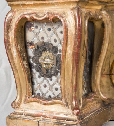 Zdjęcie nr 13: Feretron dwustronny  z obrazami świętej Anny Samotrzeć oraz św. Jana Kantego adorującego Matkę Boską  z Dzieciątkiem ustawiony na niskim postumencie o fantazyjnym kształcie z osią główną wysuniętą do przodu oraz narożnikami ustawionymi ukośnie.  W postumencie dziewięć przeszklonych gablotek mieszczących relikwie świętych, które opisane są na małych karteczkach, otoczone różnego rodzaju kwiatkami  i gwiazdkami wykonanymi z papieru i cienkich blaszek. Otwory gablotek  o różnorodnym, opływowym wykroju. Po bokach, na górnej powierzchni podstawy małe otwory po zatkniętych w nich, niezachowanych rzeźbach apostołów. Rama  w kształcie stojącego prostokąta, ujęta po każdej stronie trzema gablotkami otoczonymi rzeźbionym ornamentem rocaille&#039;owym. W zwieńczeniu takie same, mniejsze gablotki, pośrodku zamiast relikwii ażurowa, rzeźbiona wić roślinna. Na rewersie struktura feretronu o takim samym kształcie. Podstawa zdobiona siedmioma ramkami  o fantazyjnym kształtach utworzonych z wąskich esownic. Po bokach zamiast gablotek  owoidalne pola, w których złocona, drobna kratka. Rama zdobiona ornamentem rocaille&#039;owym.

Na awersie obraz z przedstawieniem św. Anny Samotrzeć. W centrum kompozycji ukazane są w postawie siedzącej św. Anna po prawej stronie i Matka Boska z Dzieciątkiem Jezus po lewej stronie. Maria zwrócona trzy czwarte w lewo, rękami przytrzymująca siedzące na jej kolanach Dzieciątko. Twarz owalna, z wyraźnie zaznaczonym podbródkiem, małe i jasnoróżowe usta, długi i szeroki nos, oczy lekko przymknięte, wysokie czoło. Włosy długie, falowane, z przedziałkiem pośrodku opadające na plecy i prawe ramię. Ubrana jest w długą, różową suknię ze złotym obszyciem pod szyją i na rękawach; niebieski płaszcz z brązową podszewką, zarzucony na plecy i otulający kolana oraz biały, delikatny welon  na głowie. Dzieciątko Jezus ukazane jest frontalnie, z lewą rączką uniesioną w geście błogosławieństwa. Twarz szeroka  z długim i szerokim nosem, wysokim czołem. Włosy krótkie, jasne, kędzierzawe. Wokół bioder ma założoną białą pieluszkę. Święta Anna zwrócona trzy czwarte w prawo,  z głową widoczną z lewego profilu, z lewą ręką przytrzymująca lewą rączkę Dzieciątka. Twarz podłużna z długim i szerokim nosem. Ubrana jest w długą zieloną suknię z długimi rękawami, czerwony płaszcz przerzucony  przez prawe ramię i zasłaniający kolana oraz jasnobrązową chustę zakrywającą włosy  i szyję. Karnacja ciemna. Wokół głów postaci złote, okrągłe nimby. W dolnej części obrazu widoczna roślinność, w górnej szarobłękitne niebo.

Na rewersie obraz z przedstawieniem Matki Boskiej z Dzieciątkiem adorowanych przez św. Jana Kantego. Scena zakomponowana  w architektonicznym wnętrzu. Maria ukazana w lewym górnym narożu obrazu,  w pozycji siedzącej na obłoku, zwrócona trzy czwarte w lewo, rękami przytrzymująca stojące na jej kolanach Dzieciątko. Twarz owalna z długim i wąskim nosem. Włosy długie, kręcone, ciemnobrązowe, schowane pod chustą. Ubrana w jasnoróżową suknię z długimi rękawami, niebieski płaszcz zasłaniający kolana, brązową chustę na głowie; na stopach sandały. Dzieciątko ukazane w pozycji stojącej, z lewą rączką wyciągniętą przed siebie, otulone przez Marię białą chustą na wysokości bioder. Diagonalnie, w dolnym, prawym narożu obrazu ukazany św. Jan Kanty; zwrócony trzy czwarte w prawo; z rękami wzniesionymi w geście modlitwy; z głową widoczną z lewego profilu, zwróconą w stronę Marii. Ubrany jest w togę profesorską. Twarz podłużna z długim i wąskim nosem, okolona krótko przystrzyżoną, siwą brodą. Włosy średniej długości, zwinięte w siwe pukle. Wokół głowy złoty, okrągły nimb. W dolnym narożu obrazu, na kamiennej posadzce otwarta, zapisana księga oraz zielona palma. Tło architektoniczne, po prawej stronie widoczna ostrołukowa arkada.

Relikwie umieszczone w niewielkich wnękach, za szybkami, opisane. Zwieńczenie feretronu, od lewej: relikwie „Sancti Vincentii Martyr”, relikwie „Sanctae Perpentuae Martyr”. Prawy bok feretronu, od góry: relikwie „Sancti Longina Męczennika”; relikwie  „Sanctae Kunegundy Panny”; relikwie „Mafsa SS. MM.”, „Sanctae Victorii Martyr”, „Sanctae Agnészki Panny i [...]”. Podstawa feretronu, od lewej: relikwie „Sancti Grzegorza Papieża”; relikwie „Sanctae Katarzyny”; relikwie „sanctus Clarus martyr”; relikwie „Sanctae Theogeni Martyr”; relikwie  „Sancti Urbana Papieża, Pluvium. Mino., Świętych Męczenników, Sanctae Gratii Marii”; relikwie „Sancti Theodori Martyr.”; relikwie „Sancti Jucundi Martyr”; relikwie „Iňocentii XI.”; relikwie „Sancti Jana Kapistrana”. Lewy bok feretronu, od góry: relikwie „Sancti Jana Kantego”; relikwie  „Sanctae Jadwigi Polki”; relikwie „Sanctae Pauliny Panny Męczennicy, Sancti Celestyna Papieża Męczen.,  SANCTI STANISŁAWA BISKUPA I MĘCZENNIKA”.
