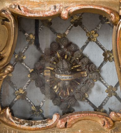 Zdjęcie nr 10: Feretron dwustronny  z obrazami świętej Anny Samotrzeć oraz św. Jana Kantego adorującego Matkę Boską  z Dzieciątkiem ustawiony na niskim postumencie o fantazyjnym kształcie z osią główną wysuniętą do przodu oraz narożnikami ustawionymi ukośnie.  W postumencie dziewięć przeszklonych gablotek mieszczących relikwie świętych, które opisane są na małych karteczkach, otoczone różnego rodzaju kwiatkami  i gwiazdkami wykonanymi z papieru i cienkich blaszek. Otwory gablotek  o różnorodnym, opływowym wykroju. Po bokach, na górnej powierzchni podstawy małe otwory po zatkniętych w nich, niezachowanych rzeźbach apostołów. Rama  w kształcie stojącego prostokąta, ujęta po każdej stronie trzema gablotkami otoczonymi rzeźbionym ornamentem rocaille&#039;owym. W zwieńczeniu takie same, mniejsze gablotki, pośrodku zamiast relikwii ażurowa, rzeźbiona wić roślinna. Na rewersie struktura feretronu o takim samym kształcie. Podstawa zdobiona siedmioma ramkami  o fantazyjnym kształtach utworzonych z wąskich esownic. Po bokach zamiast gablotek  owoidalne pola, w których złocona, drobna kratka. Rama zdobiona ornamentem rocaille&#039;owym.

Na awersie obraz z przedstawieniem św. Anny Samotrzeć. W centrum kompozycji ukazane są w postawie siedzącej św. Anna po prawej stronie i Matka Boska z Dzieciątkiem Jezus po lewej stronie. Maria zwrócona trzy czwarte w lewo, rękami przytrzymująca siedzące na jej kolanach Dzieciątko. Twarz owalna, z wyraźnie zaznaczonym podbródkiem, małe i jasnoróżowe usta, długi i szeroki nos, oczy lekko przymknięte, wysokie czoło. Włosy długie, falowane, z przedziałkiem pośrodku opadające na plecy i prawe ramię. Ubrana jest w długą, różową suknię ze złotym obszyciem pod szyją i na rękawach; niebieski płaszcz z brązową podszewką, zarzucony na plecy i otulający kolana oraz biały, delikatny welon  na głowie. Dzieciątko Jezus ukazane jest frontalnie, z lewą rączką uniesioną w geście błogosławieństwa. Twarz szeroka  z długim i szerokim nosem, wysokim czołem. Włosy krótkie, jasne, kędzierzawe. Wokół bioder ma założoną białą pieluszkę. Święta Anna zwrócona trzy czwarte w prawo,  z głową widoczną z lewego profilu, z lewą ręką przytrzymująca lewą rączkę Dzieciątka. Twarz podłużna z długim i szerokim nosem. Ubrana jest w długą zieloną suknię z długimi rękawami, czerwony płaszcz przerzucony  przez prawe ramię i zasłaniający kolana oraz jasnobrązową chustę zakrywającą włosy  i szyję. Karnacja ciemna. Wokół głów postaci złote, okrągłe nimby. W dolnej części obrazu widoczna roślinność, w górnej szarobłękitne niebo.

Na rewersie obraz z przedstawieniem Matki Boskiej z Dzieciątkiem adorowanych przez św. Jana Kantego. Scena zakomponowana  w architektonicznym wnętrzu. Maria ukazana w lewym górnym narożu obrazu,  w pozycji siedzącej na obłoku, zwrócona trzy czwarte w lewo, rękami przytrzymująca stojące na jej kolanach Dzieciątko. Twarz owalna z długim i wąskim nosem. Włosy długie, kręcone, ciemnobrązowe, schowane pod chustą. Ubrana w jasnoróżową suknię z długimi rękawami, niebieski płaszcz zasłaniający kolana, brązową chustę na głowie; na stopach sandały. Dzieciątko ukazane w pozycji stojącej, z lewą rączką wyciągniętą przed siebie, otulone przez Marię białą chustą na wysokości bioder. Diagonalnie, w dolnym, prawym narożu obrazu ukazany św. Jan Kanty; zwrócony trzy czwarte w prawo; z rękami wzniesionymi w geście modlitwy; z głową widoczną z lewego profilu, zwróconą w stronę Marii. Ubrany jest w togę profesorską. Twarz podłużna z długim i wąskim nosem, okolona krótko przystrzyżoną, siwą brodą. Włosy średniej długości, zwinięte w siwe pukle. Wokół głowy złoty, okrągły nimb. W dolnym narożu obrazu, na kamiennej posadzce otwarta, zapisana księga oraz zielona palma. Tło architektoniczne, po prawej stronie widoczna ostrołukowa arkada.

Relikwie umieszczone w niewielkich wnękach, za szybkami, opisane. Zwieńczenie feretronu, od lewej: relikwie „Sancti Vincentii Martyr”, relikwie „Sanctae Perpentuae Martyr”. Prawy bok feretronu, od góry: relikwie „Sancti Longina Męczennika”; relikwie  „Sanctae Kunegundy Panny”; relikwie „Mafsa SS. MM.”, „Sanctae Victorii Martyr”, „Sanctae Agnészki Panny i [...]”. Podstawa feretronu, od lewej: relikwie „Sancti Grzegorza Papieża”; relikwie „Sanctae Katarzyny”; relikwie „sanctus Clarus martyr”; relikwie „Sanctae Theogeni Martyr”; relikwie  „Sancti Urbana Papieża, Pluvium. Mino., Świętych Męczenników, Sanctae Gratii Marii”; relikwie „Sancti Theodori Martyr.”; relikwie „Sancti Jucundi Martyr”; relikwie „Iňocentii XI.”; relikwie „Sancti Jana Kapistrana”. Lewy bok feretronu, od góry: relikwie „Sancti Jana Kantego”; relikwie  „Sanctae Jadwigi Polki”; relikwie „Sanctae Pauliny Panny Męczennicy, Sancti Celestyna Papieża Męczen.,  SANCTI STANISŁAWA BISKUPA I MĘCZENNIKA”.
