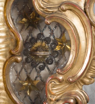 Zdjęcie nr 26: Feretron dwustronny  z obrazami świętej Anny Samotrzeć oraz św. Jana Kantego adorującego Matkę Boską  z Dzieciątkiem ustawiony na niskim postumencie o fantazyjnym kształcie z osią główną wysuniętą do przodu oraz narożnikami ustawionymi ukośnie.  W postumencie dziewięć przeszklonych gablotek mieszczących relikwie świętych, które opisane są na małych karteczkach, otoczone różnego rodzaju kwiatkami  i gwiazdkami wykonanymi z papieru i cienkich blaszek. Otwory gablotek  o różnorodnym, opływowym wykroju. Po bokach, na górnej powierzchni podstawy małe otwory po zatkniętych w nich, niezachowanych rzeźbach apostołów. Rama  w kształcie stojącego prostokąta, ujęta po każdej stronie trzema gablotkami otoczonymi rzeźbionym ornamentem rocaille'owym. W zwieńczeniu takie same, mniejsze gablotki, pośrodku zamiast relikwii ażurowa, rzeźbiona wić roślinna. Na rewersie struktura feretronu o takim samym kształcie. Podstawa zdobiona siedmioma ramkami  o fantazyjnym kształtach utworzonych z wąskich esownic. Po bokach zamiast gablotek  owoidalne pola, w których złocona, drobna kratka. Rama zdobiona ornamentem rocaille'owym.

Na awersie obraz z przedstawieniem św. Anny Samotrzeć. W centrum kompozycji ukazane są w postawie siedzącej św. Anna po prawej stronie i Matka Boska z Dzieciątkiem Jezus po lewej stronie. Maria zwrócona trzy czwarte w lewo, rękami przytrzymująca siedzące na jej kolanach Dzieciątko. Twarz owalna, z wyraźnie zaznaczonym podbródkiem, małe i jasnoróżowe usta, długi i szeroki nos, oczy lekko przymknięte, wysokie czoło. Włosy długie, falowane, z przedziałkiem pośrodku opadające na plecy i prawe ramię. Ubrana jest w długą, różową suknię ze złotym obszyciem pod szyją i na rękawach; niebieski płaszcz z brązową podszewką, zarzucony na plecy i otulający kolana oraz biały, delikatny welon  na głowie. Dzieciątko Jezus ukazane jest frontalnie, z lewą rączką uniesioną w geście błogosławieństwa. Twarz szeroka  z długim i szerokim nosem, wysokim czołem. Włosy krótkie, jasne, kędzierzawe. Wokół bioder ma założoną białą pieluszkę. Święta Anna zwrócona trzy czwarte w prawo,  z głową widoczną z lewego profilu, z lewą ręką przytrzymująca lewą rączkę Dzieciątka. Twarz podłużna z długim i szerokim nosem. Ubrana jest w długą zieloną suknię z długimi rękawami, czerwony płaszcz przerzucony  przez prawe ramię i zasłaniający kolana oraz jasnobrązową chustę zakrywającą włosy  i szyję. Karnacja ciemna. Wokół głów postaci złote, okrągłe nimby. W dolnej części obrazu widoczna roślinność, w górnej szarobłękitne niebo.

Na rewersie obraz z przedstawieniem Matki Boskiej z Dzieciątkiem adorowanych przez św. Jana Kantego. Scena zakomponowana  w architektonicznym wnętrzu. Maria ukazana w lewym górnym narożu obrazu,  w pozycji siedzącej na obłoku, zwrócona trzy czwarte w lewo, rękami przytrzymująca stojące na jej kolanach Dzieciątko. Twarz owalna z długim i wąskim nosem. Włosy długie, kręcone, ciemnobrązowe, schowane pod chustą. Ubrana w jasnoróżową suknię z długimi rękawami, niebieski płaszcz zasłaniający kolana, brązową chustę na głowie; na stopach sandały. Dzieciątko ukazane w pozycji stojącej, z lewą rączką wyciągniętą przed siebie, otulone przez Marię białą chustą na wysokości bioder. Diagonalnie, w dolnym, prawym narożu obrazu ukazany św. Jan Kanty; zwrócony trzy czwarte w prawo; z rękami wzniesionymi w geście modlitwy; z głową widoczną z lewego profilu, zwróconą w stronę Marii. Ubrany jest w togę profesorską. Twarz podłużna z długim i wąskim nosem, okolona krótko przystrzyżoną, siwą brodą. Włosy średniej długości, zwinięte w siwe pukle. Wokół głowy złoty, okrągły nimb. W dolnym narożu obrazu, na kamiennej posadzce otwarta, zapisana księga oraz zielona palma. Tło architektoniczne, po prawej stronie widoczna ostrołukowa arkada.

Relikwie umieszczone w niewielkich wnękach, za szybkami, opisane. Zwieńczenie feretronu, od lewej: relikwie „Sancti Vincentii Martyr”, relikwie „Sanctae Perpentuae Martyr”. Prawy bok feretronu, od góry: relikwie „Sancti Longina Męczennika”; relikwie  „Sanctae Kunegundy Panny”; relikwie „Mafsa SS. MM.”, „Sanctae Victorii Martyr”, „Sanctae Agnészki Panny i [...]”. Podstawa feretronu, od lewej: relikwie „Sancti Grzegorza Papieża”; relikwie „Sanctae Katarzyny”; relikwie „sanctus Clarus martyr”; relikwie „Sanctae Theogeni Martyr”; relikwie  „Sancti Urbana Papieża, Pluvium. Mino., Świętych Męczenników, Sanctae Gratii Marii”; relikwie „Sancti Theodori Martyr.”; relikwie „Sancti Jucundi Martyr”; relikwie „Iňocentii XI.”; relikwie „Sancti Jana Kapistrana”. Lewy bok feretronu, od góry: relikwie „Sancti Jana Kantego”; relikwie  „Sanctae Jadwigi Polki”; relikwie „Sanctae Pauliny Panny Męczennicy, Sancti Celestyna Papieża Męczen.,  SANCTI STANISŁAWA BISKUPA I MĘCZENNIKA”.
