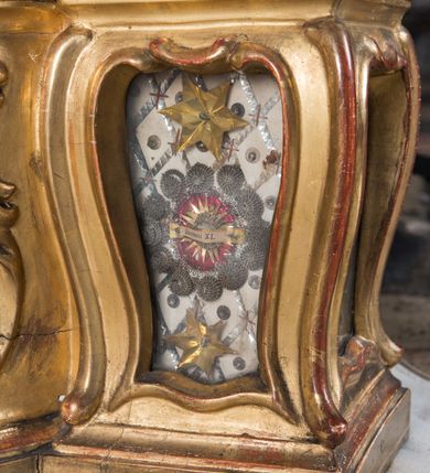 Zdjęcie nr 29: Feretron dwustronny  z obrazami świętej Anny Samotrzeć oraz św. Jana Kantego adorującego Matkę Boską  z Dzieciątkiem ustawiony na niskim postumencie o fantazyjnym kształcie z osią główną wysuniętą do przodu oraz narożnikami ustawionymi ukośnie.  W postumencie dziewięć przeszklonych gablotek mieszczących relikwie świętych, które opisane są na małych karteczkach, otoczone różnego rodzaju kwiatkami  i gwiazdkami wykonanymi z papieru i cienkich blaszek. Otwory gablotek  o różnorodnym, opływowym wykroju. Po bokach, na górnej powierzchni podstawy małe otwory po zatkniętych w nich, niezachowanych rzeźbach apostołów. Rama  w kształcie stojącego prostokąta, ujęta po każdej stronie trzema gablotkami otoczonymi rzeźbionym ornamentem rocaille'owym. W zwieńczeniu takie same, mniejsze gablotki, pośrodku zamiast relikwii ażurowa, rzeźbiona wić roślinna. Na rewersie struktura feretronu o takim samym kształcie. Podstawa zdobiona siedmioma ramkami  o fantazyjnym kształtach utworzonych z wąskich esownic. Po bokach zamiast gablotek  owoidalne pola, w których złocona, drobna kratka. Rama zdobiona ornamentem rocaille'owym.

Na awersie obraz z przedstawieniem św. Anny Samotrzeć. W centrum kompozycji ukazane są w postawie siedzącej św. Anna po prawej stronie i Matka Boska z Dzieciątkiem Jezus po lewej stronie. Maria zwrócona trzy czwarte w lewo, rękami przytrzymująca siedzące na jej kolanach Dzieciątko. Twarz owalna, z wyraźnie zaznaczonym podbródkiem, małe i jasnoróżowe usta, długi i szeroki nos, oczy lekko przymknięte, wysokie czoło. Włosy długie, falowane, z przedziałkiem pośrodku opadające na plecy i prawe ramię. Ubrana jest w długą, różową suknię ze złotym obszyciem pod szyją i na rękawach; niebieski płaszcz z brązową podszewką, zarzucony na plecy i otulający kolana oraz biały, delikatny welon  na głowie. Dzieciątko Jezus ukazane jest frontalnie, z lewą rączką uniesioną w geście błogosławieństwa. Twarz szeroka  z długim i szerokim nosem, wysokim czołem. Włosy krótkie, jasne, kędzierzawe. Wokół bioder ma założoną białą pieluszkę. Święta Anna zwrócona trzy czwarte w prawo,  z głową widoczną z lewego profilu, z lewą ręką przytrzymująca lewą rączkę Dzieciątka. Twarz podłużna z długim i szerokim nosem. Ubrana jest w długą zieloną suknię z długimi rękawami, czerwony płaszcz przerzucony  przez prawe ramię i zasłaniający kolana oraz jasnobrązową chustę zakrywającą włosy  i szyję. Karnacja ciemna. Wokół głów postaci złote, okrągłe nimby. W dolnej części obrazu widoczna roślinność, w górnej szarobłękitne niebo.

Na rewersie obraz z przedstawieniem Matki Boskiej z Dzieciątkiem adorowanych przez św. Jana Kantego. Scena zakomponowana  w architektonicznym wnętrzu. Maria ukazana w lewym górnym narożu obrazu,  w pozycji siedzącej na obłoku, zwrócona trzy czwarte w lewo, rękami przytrzymująca stojące na jej kolanach Dzieciątko. Twarz owalna z długim i wąskim nosem. Włosy długie, kręcone, ciemnobrązowe, schowane pod chustą. Ubrana w jasnoróżową suknię z długimi rękawami, niebieski płaszcz zasłaniający kolana, brązową chustę na głowie; na stopach sandały. Dzieciątko ukazane w pozycji stojącej, z lewą rączką wyciągniętą przed siebie, otulone przez Marię białą chustą na wysokości bioder. Diagonalnie, w dolnym, prawym narożu obrazu ukazany św. Jan Kanty; zwrócony trzy czwarte w prawo; z rękami wzniesionymi w geście modlitwy; z głową widoczną z lewego profilu, zwróconą w stronę Marii. Ubrany jest w togę profesorską. Twarz podłużna z długim i wąskim nosem, okolona krótko przystrzyżoną, siwą brodą. Włosy średniej długości, zwinięte w siwe pukle. Wokół głowy złoty, okrągły nimb. W dolnym narożu obrazu, na kamiennej posadzce otwarta, zapisana księga oraz zielona palma. Tło architektoniczne, po prawej stronie widoczna ostrołukowa arkada.

Relikwie umieszczone w niewielkich wnękach, za szybkami, opisane. Zwieńczenie feretronu, od lewej: relikwie „Sancti Vincentii Martyr”, relikwie „Sanctae Perpentuae Martyr”. Prawy bok feretronu, od góry: relikwie „Sancti Longina Męczennika”; relikwie  „Sanctae Kunegundy Panny”; relikwie „Mafsa SS. MM.”, „Sanctae Victorii Martyr”, „Sanctae Agnészki Panny i [...]”. Podstawa feretronu, od lewej: relikwie „Sancti Grzegorza Papieża”; relikwie „Sanctae Katarzyny”; relikwie „sanctus Clarus martyr”; relikwie „Sanctae Theogeni Martyr”; relikwie  „Sancti Urbana Papieża, Pluvium. Mino., Świętych Męczenników, Sanctae Gratii Marii”; relikwie „Sancti Theodori Martyr.”; relikwie „Sancti Jucundi Martyr”; relikwie „Iňocentii XI.”; relikwie „Sancti Jana Kapistrana”. Lewy bok feretronu, od góry: relikwie „Sancti Jana Kantego”; relikwie  „Sanctae Jadwigi Polki”; relikwie „Sanctae Pauliny Panny Męczennicy, Sancti Celestyna Papieża Męczen.,  SANCTI STANISŁAWA BISKUPA I MĘCZENNIKA”.
