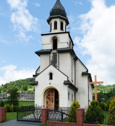 Zdjęcie nr 2: Kościół Niepokalanego Serca Najświętszej Marii Panny w Hucisku usytuowany jest w południowo-zachodniej części wsi. Plac przykościelny otoczony jest żeliwnym płotem z murowanymi słupkami. Kościół skierowany jest na zachód, murowany, otynkowany z wieżą od wschodu. Wnętrze świątyni tworzy niewielkie, prostokątne, prezbiterium zakończone trójbocznie. Nawa jest szersza, na planie prostokąta, nakryta stropem, oddzielona od prezbiterium szeroką, półkoliście zamkniętą arkadą w ścianie tęczowej. Od południa do prezbiterium przylega założona na planie prostokąta niewielka zakrystia. Na wschodniej ścianie kościoła drewniany chór muzyczny, wsparty na dwóch filarach jest dostępny schodami od południowej strony nawy. Nawę oświetlają umieszczone w północnych i południowych ścianach prostokątne, zamknięte półkoliście okna, po trzy z każdej strony. Do świątyni prowadzą dwa wejścia: główne od strony wschodniej, drugie przez zakrystię. Wejście główne prowadzi poprzez dwuskrzydłowe drzwi z kruchty pod wieżą. 

W zewnętrznej elewacji kościoła widoczny jest niewysoki, kamienny cokół, wykonany z regularnych ciosów kamienia. Prezbiterium jest niższe od nawy. Do wschodniej fasady kościoła dostawiono założoną na planie kwadratu dwukondygnacyjną wieżę-dzwonnicę, ustawioną na kruchcie na planie prostokąta. Kruchta została zamknięta trójkątnym szczytem; w jej polu znajduje się głęboka wnęka w kształcie stojącego prostokąta, zamknięta łukiem półkolistym. Poszczególne kondygnacje wieży rozdzielone są daszkami i przeprute otworami okiennymi. Całość zwieńczono wieloboczną latarnią oraz cebulastym hełmem z łacińskim krzyżem. Prezbiterium i nawa przykryte są oddzielnie, stromymi dachami dwuspadowymi. Na środku nawy znajduje się wieżyczka na sygnaturkę z latarnią i cebulastym hełmem. 