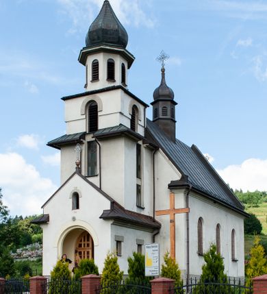 Zdjęcie nr 1: Kościół Niepokalanego Serca Najświętszej Marii Panny w Hucisku usytuowany jest w południowo-zachodniej części wsi. Plac przykościelny otoczony jest żeliwnym płotem z murowanymi słupkami. Kościół skierowany jest na zachód, murowany, otynkowany z wieżą od wschodu. Wnętrze świątyni tworzy niewielkie, prostokątne, prezbiterium zakończone trójbocznie. Nawa jest szersza, na planie prostokąta, nakryta stropem, oddzielona od prezbiterium szeroką, półkoliście zamkniętą arkadą w ścianie tęczowej. Od południa do prezbiterium przylega założona na planie prostokąta niewielka zakrystia. Na wschodniej ścianie kościoła drewniany chór muzyczny, wsparty na dwóch filarach jest dostępny schodami od południowej strony nawy. Nawę oświetlają umieszczone w północnych i południowych ścianach prostokątne, zamknięte półkoliście okna, po trzy z każdej strony. Do świątyni prowadzą dwa wejścia: główne od strony wschodniej, drugie przez zakrystię. Wejście główne prowadzi poprzez dwuskrzydłowe drzwi z kruchty pod wieżą. 

W zewnętrznej elewacji kościoła widoczny jest niewysoki, kamienny cokół, wykonany z regularnych ciosów kamienia. Prezbiterium jest niższe od nawy. Do wschodniej fasady kościoła dostawiono założoną na planie kwadratu dwukondygnacyjną wieżę-dzwonnicę, ustawioną na kruchcie na planie prostokąta. Kruchta została zamknięta trójkątnym szczytem; w jej polu znajduje się głęboka wnęka w kształcie stojącego prostokąta, zamknięta łukiem półkolistym. Poszczególne kondygnacje wieży rozdzielone są daszkami i przeprute otworami okiennymi. Całość zwieńczono wieloboczną latarnią oraz cebulastym hełmem z łacińskim krzyżem. Prezbiterium i nawa przykryte są oddzielnie, stromymi dachami dwuspadowymi. Na środku nawy znajduje się wieżyczka na sygnaturkę z latarnią i cebulastym hełmem. 