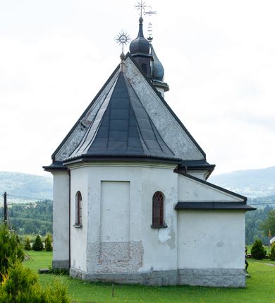 Zdjęcie nr 12: Kościół Niepokalanego Serca Najświętszej Marii Panny w Hucisku usytuowany jest w południowo-zachodniej części wsi. Plac przykościelny otoczony jest żeliwnym płotem z murowanymi słupkami. Kościół skierowany jest na zachód, murowany, otynkowany z wieżą od wschodu. Wnętrze świątyni tworzy niewielkie, prostokątne, prezbiterium zakończone trójbocznie. Nawa jest szersza, na planie prostokąta, nakryta stropem, oddzielona od prezbiterium szeroką, półkoliście zamkniętą arkadą w ścianie tęczowej. Od południa do prezbiterium przylega założona na planie prostokąta niewielka zakrystia. Na wschodniej ścianie kościoła drewniany chór muzyczny, wsparty na dwóch filarach jest dostępny schodami od południowej strony nawy. Nawę oświetlają umieszczone w północnych i południowych ścianach prostokątne, zamknięte półkoliście okna, po trzy z każdej strony. Do świątyni prowadzą dwa wejścia: główne od strony wschodniej, drugie przez zakrystię. Wejście główne prowadzi poprzez dwuskrzydłowe drzwi z kruchty pod wieżą. 

W zewnętrznej elewacji kościoła widoczny jest niewysoki, kamienny cokół, wykonany z regularnych ciosów kamienia. Prezbiterium jest niższe od nawy. Do wschodniej fasady kościoła dostawiono założoną na planie kwadratu dwukondygnacyjną wieżę-dzwonnicę, ustawioną na kruchcie na planie prostokąta. Kruchta została zamknięta trójkątnym szczytem; w jej polu znajduje się głęboka wnęka w kształcie stojącego prostokąta, zamknięta łukiem półkolistym. Poszczególne kondygnacje wieży rozdzielone są daszkami i przeprute otworami okiennymi. Całość zwieńczono wieloboczną latarnią oraz cebulastym hełmem z łacińskim krzyżem. Prezbiterium i nawa przykryte są oddzielnie, stromymi dachami dwuspadowymi. Na środku nawy znajduje się wieżyczka na sygnaturkę z latarnią i cebulastym hełmem. 