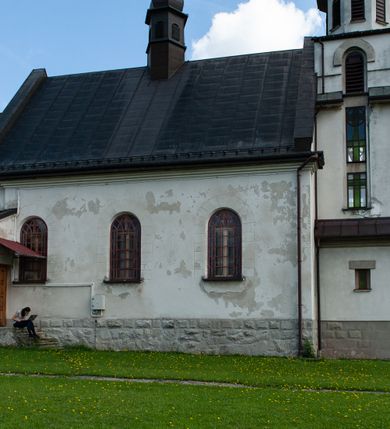 Zdjęcie nr 9: Kościół Niepokalanego Serca Najświętszej Marii Panny w Hucisku usytuowany jest w południowo-zachodniej części wsi. Plac przykościelny otoczony jest żeliwnym płotem z murowanymi słupkami. Kościół skierowany jest na zachód, murowany, otynkowany z wieżą od wschodu. Wnętrze świątyni tworzy niewielkie, prostokątne, prezbiterium zakończone trójbocznie. Nawa jest szersza, na planie prostokąta, nakryta stropem, oddzielona od prezbiterium szeroką, półkoliście zamkniętą arkadą w ścianie tęczowej. Od południa do prezbiterium przylega założona na planie prostokąta niewielka zakrystia. Na wschodniej ścianie kościoła drewniany chór muzyczny, wsparty na dwóch filarach jest dostępny schodami od południowej strony nawy. Nawę oświetlają umieszczone w północnych i południowych ścianach prostokątne, zamknięte półkoliście okna, po trzy z każdej strony. Do świątyni prowadzą dwa wejścia: główne od strony wschodniej, drugie przez zakrystię. Wejście główne prowadzi poprzez dwuskrzydłowe drzwi z kruchty pod wieżą. 

W zewnętrznej elewacji kościoła widoczny jest niewysoki, kamienny cokół, wykonany z regularnych ciosów kamienia. Prezbiterium jest niższe od nawy. Do wschodniej fasady kościoła dostawiono założoną na planie kwadratu dwukondygnacyjną wieżę-dzwonnicę, ustawioną na kruchcie na planie prostokąta. Kruchta została zamknięta trójkątnym szczytem; w jej polu znajduje się głęboka wnęka w kształcie stojącego prostokąta, zamknięta łukiem półkolistym. Poszczególne kondygnacje wieży rozdzielone są daszkami i przeprute otworami okiennymi. Całość zwieńczono wieloboczną latarnią oraz cebulastym hełmem z łacińskim krzyżem. Prezbiterium i nawa przykryte są oddzielnie, stromymi dachami dwuspadowymi. Na środku nawy znajduje się wieżyczka na sygnaturkę z latarnią i cebulastym hełmem. 