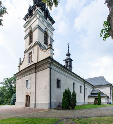 Zdjęcie nr 2: Kościół usytuowany jest w centrum miejscowości. Na plac kościelny prowadzi główne wejście od strony zachodniej oraz dwa mniejsze od strony północnej i południowej. Świątynia założona jest na planie krzyża łacińskiego, prezbiterium skierowane na zachód, równe szerokości nawy. Do korpusu kościoła przylega od strony zachodniej niższa i węższa zakrystia, a od strony południowej kruchta. Główne wejście do kościoła znajduje się od strony wschodniej przez czworoboczny przedsionek, nad którym wznosi się wieża. Portal z piaskowca, prosty o uszatych górnych narożach, w kluczu insygnia papieskie. W przedsionku od północnej strony zbudowane wewnętrzne, dwubiegowe schody kamienne prowadzące pierwotnie na chór muzyczny i wyższe piętra wieży. Na piętrze wejście do dwóch pomieszczeń usytuowanych na zapleczu chóru. Pomieszczenia te są nakryte stropami, oświetlone od południa i od wschodu. W pomieszczeniu południowym znajduje się kamienny próg z datą „1767”. Do przedsionka od strony południowej przylega kaplica Matki Boskiej Różańcowej założona na rzucie kwadratu, nakryta płaskim, malowanym stropem, wejście do kaplicy od strony północnej.

Wnętrze jest oświetlone przez 16 podłużnych okien, 8 w transepcie i 8 w ścianach nawy. Ponadto są jeszcze cztery okna okratowane, umieszczone jedno nad drugim po dwa w ścianie północnej i południowej.
Zakrystia jednoizbowa, dwa okna prostokątne w ścianie północno-zachodniej oraz dwoje drzwi, jedne do prezbiterium, drugie wejściowe w ścianie południowej. Wewnątrz zakrystii wąskie schody prowadzące do schowka na pięterku: jednoizbowego, oświetlonego od południa i od zachodu. Zakrystia i schowek nakryte płaskimi sufitami. Kruchta przybudowana do południowej ściany kościoła założona na rzucie kwadratu, o dwóch wejściach: z nawy i od zewnątrz od strony południowej. Wnętrze kościoła bez zaznaczonych podziałów architektonicznych, w dolnej części drewniana boazeria, w górnej iluzjonistyczna polichromia imitująca pilastry wspierające strop. Chór muzyczny wsparty na dwóch słupach.

Elewacja kościoła bez podziałów architektonicznych z zaznaczonym jedynie profilowanym gzymsem podokapowym. Fasada wschodnia trójosiowa ze środkowym ryzalitem, wieża włączona w korpus kościoła. W drugiej kondygnacji spływy flankujące wieżę, zakończone masywnymi sterczynami. Wieża nakryta dachem namiotowym z hełmem, na szczycie iglica. Na środku nawy ażurowa wieżyczka na sygnaturkę, nakryta daszkiem namiotowym z hełmem. Dach nad korpusem kościoła i zakrystią jednokalenicowy, dwuspadowy, nad prezbiterium i transeptem trójspadowy, nad kruchtą siodłowy.



