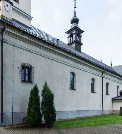 Zdjęcie nr 6: Kościół usytuowany jest w centrum miejscowości. Na plac kościelny prowadzi główne wejście od strony zachodniej oraz dwa mniejsze od strony północnej i południowej. Świątynia założona jest na planie krzyża łacińskiego, prezbiterium skierowane na zachód, równe szerokości nawy. Do korpusu kościoła przylega od strony zachodniej niższa i węższa zakrystia, a od strony południowej kruchta. Główne wejście do kościoła znajduje się od strony wschodniej przez czworoboczny przedsionek, nad którym wznosi się wieża. Portal z piaskowca, prosty o uszatych górnych narożach, w kluczu insygnia papieskie. W przedsionku od północnej strony zbudowane wewnętrzne, dwubiegowe schody kamienne prowadzące pierwotnie na chór muzyczny i wyższe piętra wieży. Na piętrze wejście do dwóch pomieszczeń usytuowanych na zapleczu chóru. Pomieszczenia te są nakryte stropami, oświetlone od południa i od wschodu. W pomieszczeniu południowym znajduje się kamienny próg z datą „1767”. Do przedsionka od strony południowej przylega kaplica Matki Boskiej Różańcowej założona na rzucie kwadratu, nakryta płaskim, malowanym stropem, wejście do kaplicy od strony północnej.

Wnętrze jest oświetlone przez 16 podłużnych okien, 8 w transepcie i 8 w ścianach nawy. Ponadto są jeszcze cztery okna okratowane, umieszczone jedno nad drugim po dwa w ścianie północnej i południowej.
Zakrystia jednoizbowa, dwa okna prostokątne w ścianie północno-zachodniej oraz dwoje drzwi, jedne do prezbiterium, drugie wejściowe w ścianie południowej. Wewnątrz zakrystii wąskie schody prowadzące do schowka na pięterku: jednoizbowego, oświetlonego od południa i od zachodu. Zakrystia i schowek nakryte płaskimi sufitami. Kruchta przybudowana do południowej ściany kościoła założona na rzucie kwadratu, o dwóch wejściach: z nawy i od zewnątrz od strony południowej. Wnętrze kościoła bez zaznaczonych podziałów architektonicznych, w dolnej części drewniana boazeria, w górnej iluzjonistyczna polichromia imitująca pilastry wspierające strop. Chór muzyczny wsparty na dwóch słupach.

Elewacja kościoła bez podziałów architektonicznych z zaznaczonym jedynie profilowanym gzymsem podokapowym. Fasada wschodnia trójosiowa ze środkowym ryzalitem, wieża włączona w korpus kościoła. W drugiej kondygnacji spływy flankujące wieżę, zakończone masywnymi sterczynami. Wieża nakryta dachem namiotowym z hełmem, na szczycie iglica. Na środku nawy ażurowa wieżyczka na sygnaturkę, nakryta daszkiem namiotowym z hełmem. Dach nad korpusem kościoła i zakrystią jednokalenicowy, dwuspadowy, nad prezbiterium i transeptem trójspadowy, nad kruchtą siodłowy.



