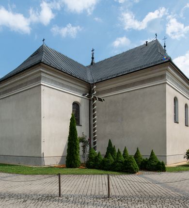 Zdjęcie nr 8: Kościół usytuowany jest w centrum miejscowości. Na plac kościelny prowadzi główne wejście od strony zachodniej oraz dwa mniejsze od strony północnej i południowej. Świątynia założona jest na planie krzyża łacińskiego, prezbiterium skierowane na zachód, równe szerokości nawy. Do korpusu kościoła przylega od strony zachodniej niższa i węższa zakrystia, a od strony południowej kruchta. Główne wejście do kościoła znajduje się od strony wschodniej przez czworoboczny przedsionek, nad którym wznosi się wieża. Portal z piaskowca, prosty o uszatych górnych narożach, w kluczu insygnia papieskie. W przedsionku od północnej strony zbudowane wewnętrzne, dwubiegowe schody kamienne prowadzące pierwotnie na chór muzyczny i wyższe piętra wieży. Na piętrze wejście do dwóch pomieszczeń usytuowanych na zapleczu chóru. Pomieszczenia te są nakryte stropami, oświetlone od południa i od wschodu. W pomieszczeniu południowym znajduje się kamienny próg z datą „1767”. Do przedsionka od strony południowej przylega kaplica Matki Boskiej Różańcowej założona na rzucie kwadratu, nakryta płaskim, malowanym stropem, wejście do kaplicy od strony północnej.

Wnętrze jest oświetlone przez 16 podłużnych okien, 8 w transepcie i 8 w ścianach nawy. Ponadto są jeszcze cztery okna okratowane, umieszczone jedno nad drugim po dwa w ścianie północnej i południowej.
Zakrystia jednoizbowa, dwa okna prostokątne w ścianie północno-zachodniej oraz dwoje drzwi, jedne do prezbiterium, drugie wejściowe w ścianie południowej. Wewnątrz zakrystii wąskie schody prowadzące do schowka na pięterku: jednoizbowego, oświetlonego od południa i od zachodu. Zakrystia i schowek nakryte płaskimi sufitami. Kruchta przybudowana do południowej ściany kościoła założona na rzucie kwadratu, o dwóch wejściach: z nawy i od zewnątrz od strony południowej. Wnętrze kościoła bez zaznaczonych podziałów architektonicznych, w dolnej części drewniana boazeria, w górnej iluzjonistyczna polichromia imitująca pilastry wspierające strop. Chór muzyczny wsparty na dwóch słupach.

Elewacja kościoła bez podziałów architektonicznych z zaznaczonym jedynie profilowanym gzymsem podokapowym. Fasada wschodnia trójosiowa ze środkowym ryzalitem, wieża włączona w korpus kościoła. W drugiej kondygnacji spływy flankujące wieżę, zakończone masywnymi sterczynami. Wieża nakryta dachem namiotowym z hełmem, na szczycie iglica. Na środku nawy ażurowa wieżyczka na sygnaturkę, nakryta daszkiem namiotowym z hełmem. Dach nad korpusem kościoła i zakrystią jednokalenicowy, dwuspadowy, nad prezbiterium i transeptem trójspadowy, nad kruchtą siodłowy.



