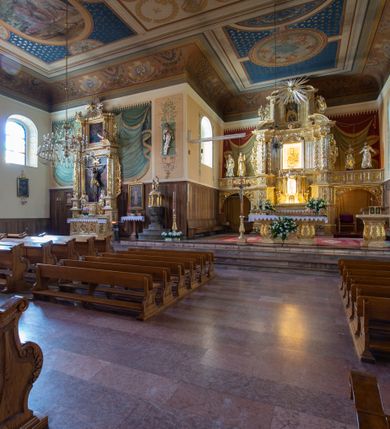 Zdjęcie nr 14: Kościół usytuowany jest w centrum miejscowości. Na plac kościelny prowadzi główne wejście od strony zachodniej oraz dwa mniejsze od strony północnej i południowej. Świątynia założona jest na planie krzyża łacińskiego, prezbiterium skierowane na zachód, równe szerokości nawy. Do korpusu kościoła przylega od strony zachodniej niższa i węższa zakrystia, a od strony południowej kruchta. Główne wejście do kościoła znajduje się od strony wschodniej przez czworoboczny przedsionek, nad którym wznosi się wieża. Portal z piaskowca, prosty o uszatych górnych narożach, w kluczu insygnia papieskie. W przedsionku od północnej strony zbudowane wewnętrzne, dwubiegowe schody kamienne prowadzące pierwotnie na chór muzyczny i wyższe piętra wieży. Na piętrze wejście do dwóch pomieszczeń usytuowanych na zapleczu chóru. Pomieszczenia te są nakryte stropami, oświetlone od południa i od wschodu. W pomieszczeniu południowym znajduje się kamienny próg z datą „1767”. Do przedsionka od strony południowej przylega kaplica Matki Boskiej Różańcowej założona na rzucie kwadratu, nakryta płaskim, malowanym stropem, wejście do kaplicy od strony północnej.

Wnętrze jest oświetlone przez 16 podłużnych okien, 8 w transepcie i 8 w ścianach nawy. Ponadto są jeszcze cztery okna okratowane, umieszczone jedno nad drugim po dwa w ścianie północnej i południowej.
Zakrystia jednoizbowa, dwa okna prostokątne w ścianie północno-zachodniej oraz dwoje drzwi, jedne do prezbiterium, drugie wejściowe w ścianie południowej. Wewnątrz zakrystii wąskie schody prowadzące do schowka na pięterku: jednoizbowego, oświetlonego od południa i od zachodu. Zakrystia i schowek nakryte płaskimi sufitami. Kruchta przybudowana do południowej ściany kościoła założona na rzucie kwadratu, o dwóch wejściach: z nawy i od zewnątrz od strony południowej. Wnętrze kościoła bez zaznaczonych podziałów architektonicznych, w dolnej części drewniana boazeria, w górnej iluzjonistyczna polichromia imitująca pilastry wspierające strop. Chór muzyczny wsparty na dwóch słupach.

Elewacja kościoła bez podziałów architektonicznych z zaznaczonym jedynie profilowanym gzymsem podokapowym. Fasada wschodnia trójosiowa ze środkowym ryzalitem, wieża włączona w korpus kościoła. W drugiej kondygnacji spływy flankujące wieżę, zakończone masywnymi sterczynami. Wieża nakryta dachem namiotowym z hełmem, na szczycie iglica. Na środku nawy ażurowa wieżyczka na sygnaturkę, nakryta daszkiem namiotowym z hełmem. Dach nad korpusem kościoła i zakrystią jednokalenicowy, dwuspadowy, nad prezbiterium i transeptem trójspadowy, nad kruchtą siodłowy.



