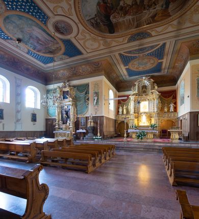 Zdjęcie nr 13: Kościół usytuowany jest w centrum miejscowości. Na plac kościelny prowadzi główne wejście od strony zachodniej oraz dwa mniejsze od strony północnej i południowej. Świątynia założona jest na planie krzyża łacińskiego, prezbiterium skierowane na zachód, równe szerokości nawy. Do korpusu kościoła przylega od strony zachodniej niższa i węższa zakrystia, a od strony południowej kruchta. Główne wejście do kościoła znajduje się od strony wschodniej przez czworoboczny przedsionek, nad którym wznosi się wieża. Portal z piaskowca, prosty o uszatych górnych narożach, w kluczu insygnia papieskie. W przedsionku od północnej strony zbudowane wewnętrzne, dwubiegowe schody kamienne prowadzące pierwotnie na chór muzyczny i wyższe piętra wieży. Na piętrze wejście do dwóch pomieszczeń usytuowanych na zapleczu chóru. Pomieszczenia te są nakryte stropami, oświetlone od południa i od wschodu. W pomieszczeniu południowym znajduje się kamienny próg z datą „1767”. Do przedsionka od strony południowej przylega kaplica Matki Boskiej Różańcowej założona na rzucie kwadratu, nakryta płaskim, malowanym stropem, wejście do kaplicy od strony północnej.

Wnętrze jest oświetlone przez 16 podłużnych okien, 8 w transepcie i 8 w ścianach nawy. Ponadto są jeszcze cztery okna okratowane, umieszczone jedno nad drugim po dwa w ścianie północnej i południowej.
Zakrystia jednoizbowa, dwa okna prostokątne w ścianie północno-zachodniej oraz dwoje drzwi, jedne do prezbiterium, drugie wejściowe w ścianie południowej. Wewnątrz zakrystii wąskie schody prowadzące do schowka na pięterku: jednoizbowego, oświetlonego od południa i od zachodu. Zakrystia i schowek nakryte płaskimi sufitami. Kruchta przybudowana do południowej ściany kościoła założona na rzucie kwadratu, o dwóch wejściach: z nawy i od zewnątrz od strony południowej. Wnętrze kościoła bez zaznaczonych podziałów architektonicznych, w dolnej części drewniana boazeria, w górnej iluzjonistyczna polichromia imitująca pilastry wspierające strop. Chór muzyczny wsparty na dwóch słupach.

Elewacja kościoła bez podziałów architektonicznych z zaznaczonym jedynie profilowanym gzymsem podokapowym. Fasada wschodnia trójosiowa ze środkowym ryzalitem, wieża włączona w korpus kościoła. W drugiej kondygnacji spływy flankujące wieżę, zakończone masywnymi sterczynami. Wieża nakryta dachem namiotowym z hełmem, na szczycie iglica. Na środku nawy ażurowa wieżyczka na sygnaturkę, nakryta daszkiem namiotowym z hełmem. Dach nad korpusem kościoła i zakrystią jednokalenicowy, dwuspadowy, nad prezbiterium i transeptem trójspadowy, nad kruchtą siodłowy.



