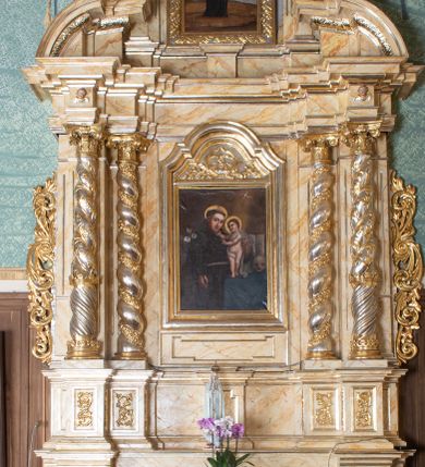 Zdjęcie nr 1: Nastawa ołtarzowa architektoniczna, dwukondygnacyjna, jednoosiowa. Ołtarz prostopadłościenny, drewniany, mensa drewniana z kamiennym portatylem. Antependium zdobione trzema prostokątnymi płycinami, zewnętrze zdobione liśćmi akantu, wewnętrza z godłem zakonu franciszkanów umieszczonym w medalionie.

Nastawa ustawiona na zdwojonym cokole, dekorowanym płycinami, wypełnionymi liśćmi akantu. Pierwsza kondygnacja flankowana pilastrami oraz ustawionymi na skraju filarami, przed nimi dwie pary kolumn, z których zewnętrzna wysunięta jest do przodu. Podpory wspierają wyłamane belkowanie i przerywany przyczółek. Trzony pilastrów i filarów kanelowane, trzony kolumn skręcone i oplecione wicią roślinną, kapitele kolumn kompozytowe. W polu głównym umieszczony jest obraz św. Antoniego Dzieciątkiem w ramie w kształcie stojącego prostokąta, zamkniętego łukiem wklęsło-wypukłym z uskokami. Nad obrazem płaskorzeźbiony wieniec chwały, dwie gałązki i sygle „S[WIĘTY] A[NTONI]”. Druga kondygnacja ujęta parą zdwojonych pilastrów. Podpory wspierają wyłamane belkowanie. W polu głównym obraz w kształcie stojącego prostokąta z przedstawieniem św. Jana Nepomucena. Trzony pilastrów kanelowane. Na szczycie umieszczona jest promienista gloria Okiem Opatrzności na tle obłoków. Po bokach zwieńczenia na wysokich cokołach figury św. Wojciecha po lewej stroni i św. Stanisława po prawej. Boki obu kondygnacji zdobione są ażurowymi uszami z liśćmi akantu. Struktura marmoryzowana w odcieniu jasnobeżowym z brązowym i czerwonym żyłkowaniem; ornamentyka, kolumny i profilowania złocone, detale srebrzone.