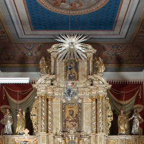 Zdjęcie nr 1: Nastawa ołtarzowa architektoniczna, dwukondygnacyjna, trójosiowa z bramkami. Ołtarz prostopadłościenny, drewniany, mensa drewniana z kamiennym portatylem. Tabernakulum i tron wystawienia w formie aediculi, na rzucie wieloboku, ustawione na wysokim cokole, w narożach flankowane kolumienkami wspierającymi profilowany gzyms; boki ujęte spływami wolutowymi i rocaille’m. W polu głównym głęboka wnęka z płaskorzeźbionym krucyfiksem, od góry zdobiona podwieszonym lambrekinem. W partii cokołowej, ujętej w narożach spływami wolutowymi umieszczone tabernakulum. Drzwiczki w kształcie stojącego prostokąta, zamknięte łukiem wklęsło-wypukłym, w polu rzeźbiony kielich z hostią. W zwieńczeniu półkopuła z rzeźbą baranka eucharystycznego na szczycie na tle promienistej glorii, po bokach figurki aniołów, a na osi zewnętrznych kolumn płomieniste wazony.

Nastawa ustawiona na potrójnym cokole, dekorowanym płycinami, wypełnionymi liśćmi akantu. Pierwsza kondygnacja flankowana szerokimi pilastrami oraz ustawionymi na skraju filarami, przed nimi dwie pary kolumn, z których zewnętrzna wysunięta jest do przodu. Podpory wspierają wyłamane belkowanie i przerywany przyczółek. Trzony pilastrów i filarów kanelowane, trzony kolumn skręcone i oplecione wicią roślinną, kapitele kolumn kompozytowe. Fryz w całości pokryty liśćmi stylizowanego akantu. W polu głównym umieszczony jest obraz Matki Boskiej z Dzieciątkiem w ramie w kształcie stojącego prostokąta, zamkniętego łukiem wklęsło-wypukłym z uskokami. Druga kondygnacja ujęta parą zdwojonych pilastrów i ustawionych przed nimi kolumnami o gładkich trzonach i kompozytowych kapitelach. Podpory wspierają wyłamane belkowanie oraz przerywany przyczółek. W polu głównym obraz w kształcie stojącego prostokąta z przedstawieniem św. Mikołaja. Po bokach struktura kondygnacji kanelowana. Na szczycie umieszczona jest promienista gloria z gołębicą Ducha Świętego. Po bokach zwieńczenia na wysokich cokołach figury dwóch świętych niewiast. Boki obu kondygnacji zdobione są ażurowymi uszami z liśćmi akantu.

Bramki w formie przedłużenia trzeciej strefy cokołowej nastawy ołtarzowej. Przejścia zdobione półkolistym, podwieszonym, ażurowym ornamentem akantowym. Na cokole ustawione rzeźby: po lewej stronie nierozpoznany święty, zapewne franciszkanin z krzyżem w dłoni oraz św. Jacek. Po prawej stronie św. Dominik oraz św. Franciszek z Asyżu. Struktura marmoryzowana w odcieniu jasnobeżowym z brązowym i czerwonym żyłkowaniem; ornamentyka, kolumny i profilowania złocone, detale srebrzone.