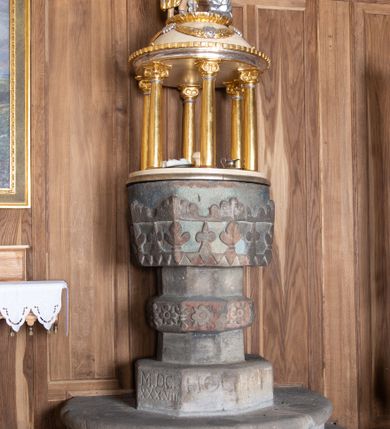 Zdjęcie nr 2: Chrzcielnica ustawiona na dwóch stopniach na rzucie półkolistym, wsparta na ośmiobocznej stopie z napisem „HOC BAPTISTERIUM EST CONSTRUCTUM MDCXXXVIII ”. Trzon ośmioboczny z ośmiobocznym pierścieniem pośrodku, ozdobionym rozetkami. Czara wysoka, ośmioboczna, zdobiona od dołu rzeźbionym ząbkowym pasem dekoracyjnym, powyżej stylizowanymi liliami andegaweńskimi, a od góry pasem liści. Pokrywa w formie małej aediculi, wsparta na sześciu kolumnach, które unoszą półkolistą kopułę. Podpory o gładkich i złoconych trzonach, kapitele jońskie. Zwieńczenie o profilowanym gzymsie, kopuła zdobiona girlandami, a na szczycie kimationem. Na kopule ustawiona grupa rzeźbiarska przedstawiająca św. Jana Chrzciciela i Chrystusa. Polichromia w odsłoniętych partiach ciała naturalistyczna, detale i ornamentyka złocone i srebrzone, kopuła polichromowana na kolor jasnobeżowy.

