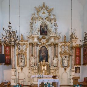 Zdjęcie nr 1: Nastawa architektoniczna, trójosiowa, dwukondygnacyjna ze zwieńczeniem, ustawiona na dwustrefowym cokole. Ołtarz drewniany, prostopadłościenny z drewnianą mensą, w partii antepedium dekorowany trzema płycinami. Na ołtarzu ustawione tabernakulum. Cokół dwustrefowy z wyodrębnionymi prostopadłościanami dekorowanymi w pierwszej strefie płycinami, w drugiej rocaille'owymi płycinami.  Osie pierwszej kondygnacji wydzielone trzema parami kolumn. Oś środkowa flankowana dwiema parami pilastrów i stojącymi przed nimi kolumnami ustawionymi na cokołach, druga para zwrócona pod kątem na zewnątrz. Podpory dźwigają wyłamane na ich osi fragmenty belkowania, środkowa para również przerwany, falisty przyczółek. Na belkowaniu i przyczółku siedzi para puttów i para adorujących aniołów. Pomiędzy parami kolumn ustawione figury św. Anny i św. Elżbiety. W polu głównym znajduje się wnęka w formie stojącego prostokąta zamkniętego łukiem półkolistym nadwieszonym z uskokiem, ujęta profilowaną ramą z obrazem Matki Boskiej z Dzieciątkiem i św. Janem Chrzcicielem. Ponad obrazem rokokowy kartusz z kwiatowymi zwisami, z napisem „EN! / PORTA PATET CURIAE / DEI EXCELSA MATER ET / VIRGO IO! VENITE / S(anctus) Cyprianus”. Osie boczne wydzielone zewnętrzną parą pilastrów i stojących przed nimi kolumn ustawionych na dwustrefowych cokołach, dźwigających imposty i fragmenty przerwanego rocaille'owego przyczółka. Na osiach w partii cokołu znajdują się bramki z drzwiami w kształcie stojącego prostokąta zamkniętego łukiem półkolistym. Ponad nimi na rocaille'owych konsolach, na tle wnęki ujętej rocaille'ową ramą znajdują się figury św. Joachima i Zachariasza. Nad wnękami ażurowa kratka w formie stojącego prostokąta ujęta rocaille'ową ramą. Całość zamknięta rocaille'm z wyodrębnionym pionowym akcentem koguciego grzebienia. Druga kondygnacja flankowana dwiema parami pilastrów, w tym zewnętrzną ustawioną pod kątem na zewnątrz o trzonach przechodzących w spływy wolutowe ustawione na cokołach na belkowaniu pierwszej kondygnacji nastawy. Spływy zakończone są rokokowymi wazonami. Podpory dźwigają gzyms przerwany na polem. Całość zamknięta medalionem z Okiem Opatrzności otoczonym wieńcem z obłoków i uskrzydlonych główek anielskich, w glorii promienistej. U dołu medalionu i na gzymsie znajdują się putta. W polu wnęka w formie stojącego prostokąta zamkniętego łukiem półkolistym nadwieszonym w profilowanej ramie z obrazem św. Kazimierza. Struktura niemal w całości polichromowana w kolorze białym, trzony kolumn polichromowane na sposób imitujący marmoryzację w kolorze biało-różowym, profile i ornamentyka złocone. 