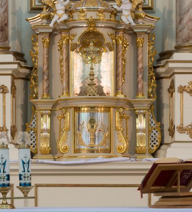 Zdjęcie nr 51: Nastawa architektoniczna, trójosiowa, dwukondygnacyjna ze zwieńczeniem, ustawiona na dwustrefowym cokole. Ołtarz drewniany, prostopadłościenny z drewnianą mensą, w partii antepedium dekorowany trzema płycinami. Na ołtarzu ustawione tabernakulum. Cokół dwustrefowy z wyodrębnionymi prostopadłościanami dekorowanymi w pierwszej strefie płycinami, w drugiej rocaille&#039;owymi płycinami.  Osie pierwszej kondygnacji wydzielone trzema parami kolumn. Oś środkowa flankowana dwiema parami pilastrów i stojącymi przed nimi kolumnami ustawionymi na cokołach, druga para zwrócona pod kątem na zewnątrz. Podpory dźwigają wyłamane na ich osi fragmenty belkowania, środkowa para również przerwany, falisty przyczółek. Na belkowaniu i przyczółku siedzi para puttów i para adorujących aniołów. Pomiędzy parami kolumn ustawione figury św. Anny i św. Elżbiety. W polu głównym znajduje się wnęka w formie stojącego prostokąta zamkniętego łukiem półkolistym nadwieszonym z uskokiem, ujęta profilowaną ramą z obrazem Matki Boskiej z Dzieciątkiem i św. Janem Chrzcicielem. Ponad obrazem rokokowy kartusz z kwiatowymi zwisami, z napisem „EN! / PORTA PATET CURIAE / DEI EXCELSA MATER ET / VIRGO IO! VENITE / S(anctus) Cyprianus”. Osie boczne wydzielone zewnętrzną parą pilastrów i stojących przed nimi kolumn ustawionych na dwustrefowych cokołach, dźwigających imposty i fragmenty przerwanego rocaille&#039;owego przyczółka. Na osiach w partii cokołu znajdują się bramki z drzwiami w kształcie stojącego prostokąta zamkniętego łukiem półkolistym. Ponad nimi na rocaille&#039;owych konsolach, na tle wnęki ujętej rocaille&#039;ową ramą znajdują się figury św. Joachima i Zachariasza. Nad wnękami ażurowa kratka w formie stojącego prostokąta ujęta rocaille&#039;ową ramą. Całość zamknięta rocaille&#039;m z wyodrębnionym pionowym akcentem koguciego grzebienia. Druga kondygnacja flankowana dwiema parami pilastrów, w tym zewnętrzną ustawioną pod kątem na zewnątrz o trzonach przechodzących w spływy wolutowe ustawione na cokołach na belkowaniu pierwszej kondygnacji nastawy. Spływy zakończone są rokokowymi wazonami. Podpory dźwigają gzyms przerwany na polem. Całość zamknięta medalionem z Okiem Opatrzności otoczonym wieńcem z obłoków i uskrzydlonych główek anielskich, w glorii promienistej. U dołu medalionu i na gzymsie znajdują się putta. W polu wnęka w formie stojącego prostokąta zamkniętego łukiem półkolistym nadwieszonym w profilowanej ramie z obrazem św. Kazimierza. Struktura niemal w całości polichromowana w kolorze białym, trzony kolumn polichromowane na sposób imitujący marmoryzację w kolorze biało-różowym, profile i ornamentyka złocone. 