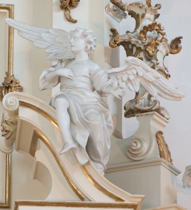 Zdjęcie nr 63: Nastawa architektoniczna, trójosiowa, dwukondygnacyjna ze zwieńczeniem, ustawiona na dwustrefowym cokole. Ołtarz drewniany, prostopadłościenny z drewnianą mensą, w partii antepedium dekorowany trzema płycinami. Na ołtarzu ustawione tabernakulum. Cokół dwustrefowy z wyodrębnionymi prostopadłościanami dekorowanymi w pierwszej strefie płycinami, w drugiej rocaille'owymi płycinami.  Osie pierwszej kondygnacji wydzielone trzema parami kolumn. Oś środkowa flankowana dwiema parami pilastrów i stojącymi przed nimi kolumnami ustawionymi na cokołach, druga para zwrócona pod kątem na zewnątrz. Podpory dźwigają wyłamane na ich osi fragmenty belkowania, środkowa para również przerwany, falisty przyczółek. Na belkowaniu i przyczółku siedzi para puttów i para adorujących aniołów. Pomiędzy parami kolumn ustawione figury św. Anny i św. Elżbiety. W polu głównym znajduje się wnęka w formie stojącego prostokąta zamkniętego łukiem półkolistym nadwieszonym z uskokiem, ujęta profilowaną ramą z obrazem Matki Boskiej z Dzieciątkiem i św. Janem Chrzcicielem. Ponad obrazem rokokowy kartusz z kwiatowymi zwisami, z napisem „EN! / PORTA PATET CURIAE / DEI EXCELSA MATER ET / VIRGO IO! VENITE / S(anctus) Cyprianus”. Osie boczne wydzielone zewnętrzną parą pilastrów i stojących przed nimi kolumn ustawionych na dwustrefowych cokołach, dźwigających imposty i fragmenty przerwanego rocaille'owego przyczółka. Na osiach w partii cokołu znajdują się bramki z drzwiami w kształcie stojącego prostokąta zamkniętego łukiem półkolistym. Ponad nimi na rocaille'owych konsolach, na tle wnęki ujętej rocaille'ową ramą znajdują się figury św. Joachima i Zachariasza. Nad wnękami ażurowa kratka w formie stojącego prostokąta ujęta rocaille'ową ramą. Całość zamknięta rocaille'm z wyodrębnionym pionowym akcentem koguciego grzebienia. Druga kondygnacja flankowana dwiema parami pilastrów, w tym zewnętrzną ustawioną pod kątem na zewnątrz o trzonach przechodzących w spływy wolutowe ustawione na cokołach na belkowaniu pierwszej kondygnacji nastawy. Spływy zakończone są rokokowymi wazonami. Podpory dźwigają gzyms przerwany na polem. Całość zamknięta medalionem z Okiem Opatrzności otoczonym wieńcem z obłoków i uskrzydlonych główek anielskich, w glorii promienistej. U dołu medalionu i na gzymsie znajdują się putta. W polu wnęka w formie stojącego prostokąta zamkniętego łukiem półkolistym nadwieszonym w profilowanej ramie z obrazem św. Kazimierza. Struktura niemal w całości polichromowana w kolorze białym, trzony kolumn polichromowane na sposób imitujący marmoryzację w kolorze biało-różowym, profile i ornamentyka złocone. 