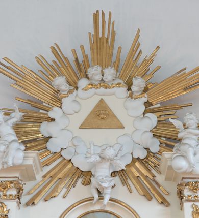 Zdjęcie nr 61: Nastawa architektoniczna, trójosiowa, dwukondygnacyjna ze zwieńczeniem, ustawiona na dwustrefowym cokole. Ołtarz drewniany, prostopadłościenny z drewnianą mensą, w partii antepedium dekorowany trzema płycinami. Na ołtarzu ustawione tabernakulum. Cokół dwustrefowy z wyodrębnionymi prostopadłościanami dekorowanymi w pierwszej strefie płycinami, w drugiej rocaille'owymi płycinami.  Osie pierwszej kondygnacji wydzielone trzema parami kolumn. Oś środkowa flankowana dwiema parami pilastrów i stojącymi przed nimi kolumnami ustawionymi na cokołach, druga para zwrócona pod kątem na zewnątrz. Podpory dźwigają wyłamane na ich osi fragmenty belkowania, środkowa para również przerwany, falisty przyczółek. Na belkowaniu i przyczółku siedzi para puttów i para adorujących aniołów. Pomiędzy parami kolumn ustawione figury św. Anny i św. Elżbiety. W polu głównym znajduje się wnęka w formie stojącego prostokąta zamkniętego łukiem półkolistym nadwieszonym z uskokiem, ujęta profilowaną ramą z obrazem Matki Boskiej z Dzieciątkiem i św. Janem Chrzcicielem. Ponad obrazem rokokowy kartusz z kwiatowymi zwisami, z napisem „EN! / PORTA PATET CURIAE / DEI EXCELSA MATER ET / VIRGO IO! VENITE / S(anctus) Cyprianus”. Osie boczne wydzielone zewnętrzną parą pilastrów i stojących przed nimi kolumn ustawionych na dwustrefowych cokołach, dźwigających imposty i fragmenty przerwanego rocaille'owego przyczółka. Na osiach w partii cokołu znajdują się bramki z drzwiami w kształcie stojącego prostokąta zamkniętego łukiem półkolistym. Ponad nimi na rocaille'owych konsolach, na tle wnęki ujętej rocaille'ową ramą znajdują się figury św. Joachima i Zachariasza. Nad wnękami ażurowa kratka w formie stojącego prostokąta ujęta rocaille'ową ramą. Całość zamknięta rocaille'm z wyodrębnionym pionowym akcentem koguciego grzebienia. Druga kondygnacja flankowana dwiema parami pilastrów, w tym zewnętrzną ustawioną pod kątem na zewnątrz o trzonach przechodzących w spływy wolutowe ustawione na cokołach na belkowaniu pierwszej kondygnacji nastawy. Spływy zakończone są rokokowymi wazonami. Podpory dźwigają gzyms przerwany na polem. Całość zamknięta medalionem z Okiem Opatrzności otoczonym wieńcem z obłoków i uskrzydlonych główek anielskich, w glorii promienistej. U dołu medalionu i na gzymsie znajdują się putta. W polu wnęka w formie stojącego prostokąta zamkniętego łukiem półkolistym nadwieszonym w profilowanej ramie z obrazem św. Kazimierza. Struktura niemal w całości polichromowana w kolorze białym, trzony kolumn polichromowane na sposób imitujący marmoryzację w kolorze biało-różowym, profile i ornamentyka złocone. 