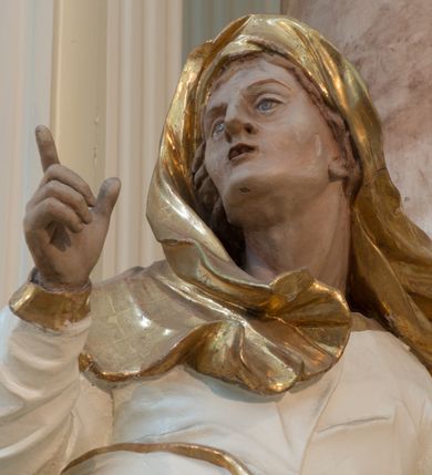 Zdjęcie nr 23: Nastawa architektoniczna, trójosiowa, dwukondygnacyjna ze zwieńczeniem, ustawiona na dwustrefowym cokole. Ołtarz drewniany, prostopadłościenny z drewnianą mensą, w partii antepedium dekorowany trzema płycinami. Na ołtarzu ustawione tabernakulum. Cokół dwustrefowy z wyodrębnionymi prostopadłościanami dekorowanymi w pierwszej strefie płycinami, w drugiej rocaille'owymi płycinami.  Osie pierwszej kondygnacji wydzielone trzema parami kolumn. Oś środkowa flankowana dwiema parami pilastrów i stojącymi przed nimi kolumnami ustawionymi na cokołach, druga para zwrócona pod kątem na zewnątrz. Podpory dźwigają wyłamane na ich osi fragmenty belkowania, środkowa para również przerwany, falisty przyczółek. Na belkowaniu i przyczółku siedzi para puttów i para adorujących aniołów. Pomiędzy parami kolumn ustawione figury św. Anny i św. Elżbiety. W polu głównym znajduje się wnęka w formie stojącego prostokąta zamkniętego łukiem półkolistym nadwieszonym z uskokiem, ujęta profilowaną ramą z obrazem Matki Boskiej z Dzieciątkiem i św. Janem Chrzcicielem. Ponad obrazem rokokowy kartusz z kwiatowymi zwisami, z napisem „EN! / PORTA PATET CURIAE / DEI EXCELSA MATER ET / VIRGO IO! VENITE / S(anctus) Cyprianus”. Osie boczne wydzielone zewnętrzną parą pilastrów i stojących przed nimi kolumn ustawionych na dwustrefowych cokołach, dźwigających imposty i fragmenty przerwanego rocaille'owego przyczółka. Na osiach w partii cokołu znajdują się bramki z drzwiami w kształcie stojącego prostokąta zamkniętego łukiem półkolistym. Ponad nimi na rocaille'owych konsolach, na tle wnęki ujętej rocaille'ową ramą znajdują się figury św. Joachima i Zachariasza. Nad wnękami ażurowa kratka w formie stojącego prostokąta ujęta rocaille'ową ramą. Całość zamknięta rocaille'm z wyodrębnionym pionowym akcentem koguciego grzebienia. Druga kondygnacja flankowana dwiema parami pilastrów, w tym zewnętrzną ustawioną pod kątem na zewnątrz o trzonach przechodzących w spływy wolutowe ustawione na cokołach na belkowaniu pierwszej kondygnacji nastawy. Spływy zakończone są rokokowymi wazonami. Podpory dźwigają gzyms przerwany na polem. Całość zamknięta medalionem z Okiem Opatrzności otoczonym wieńcem z obłoków i uskrzydlonych główek anielskich, w glorii promienistej. U dołu medalionu i na gzymsie znajdują się putta. W polu wnęka w formie stojącego prostokąta zamkniętego łukiem półkolistym nadwieszonym w profilowanej ramie z obrazem św. Kazimierza. Struktura niemal w całości polichromowana w kolorze białym, trzony kolumn polichromowane na sposób imitujący marmoryzację w kolorze biało-różowym, profile i ornamentyka złocone. 