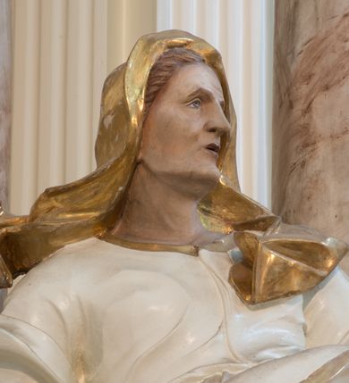 Zdjęcie nr 32: Nastawa architektoniczna, trójosiowa, dwukondygnacyjna ze zwieńczeniem, ustawiona na dwustrefowym cokole. Ołtarz drewniany, prostopadłościenny z drewnianą mensą, w partii antepedium dekorowany trzema płycinami. Na ołtarzu ustawione tabernakulum. Cokół dwustrefowy z wyodrębnionymi prostopadłościanami dekorowanymi w pierwszej strefie płycinami, w drugiej rocaille'owymi płycinami.  Osie pierwszej kondygnacji wydzielone trzema parami kolumn. Oś środkowa flankowana dwiema parami pilastrów i stojącymi przed nimi kolumnami ustawionymi na cokołach, druga para zwrócona pod kątem na zewnątrz. Podpory dźwigają wyłamane na ich osi fragmenty belkowania, środkowa para również przerwany, falisty przyczółek. Na belkowaniu i przyczółku siedzi para puttów i para adorujących aniołów. Pomiędzy parami kolumn ustawione figury św. Anny i św. Elżbiety. W polu głównym znajduje się wnęka w formie stojącego prostokąta zamkniętego łukiem półkolistym nadwieszonym z uskokiem, ujęta profilowaną ramą z obrazem Matki Boskiej z Dzieciątkiem i św. Janem Chrzcicielem. Ponad obrazem rokokowy kartusz z kwiatowymi zwisami, z napisem „EN! / PORTA PATET CURIAE / DEI EXCELSA MATER ET / VIRGO IO! VENITE / S(anctus) Cyprianus”. Osie boczne wydzielone zewnętrzną parą pilastrów i stojących przed nimi kolumn ustawionych na dwustrefowych cokołach, dźwigających imposty i fragmenty przerwanego rocaille'owego przyczółka. Na osiach w partii cokołu znajdują się bramki z drzwiami w kształcie stojącego prostokąta zamkniętego łukiem półkolistym. Ponad nimi na rocaille'owych konsolach, na tle wnęki ujętej rocaille'ową ramą znajdują się figury św. Joachima i Zachariasza. Nad wnękami ażurowa kratka w formie stojącego prostokąta ujęta rocaille'ową ramą. Całość zamknięta rocaille'm z wyodrębnionym pionowym akcentem koguciego grzebienia. Druga kondygnacja flankowana dwiema parami pilastrów, w tym zewnętrzną ustawioną pod kątem na zewnątrz o trzonach przechodzących w spływy wolutowe ustawione na cokołach na belkowaniu pierwszej kondygnacji nastawy. Spływy zakończone są rokokowymi wazonami. Podpory dźwigają gzyms przerwany na polem. Całość zamknięta medalionem z Okiem Opatrzności otoczonym wieńcem z obłoków i uskrzydlonych główek anielskich, w glorii promienistej. U dołu medalionu i na gzymsie znajdują się putta. W polu wnęka w formie stojącego prostokąta zamkniętego łukiem półkolistym nadwieszonym w profilowanej ramie z obrazem św. Kazimierza. Struktura niemal w całości polichromowana w kolorze białym, trzony kolumn polichromowane na sposób imitujący marmoryzację w kolorze biało-różowym, profile i ornamentyka złocone. 